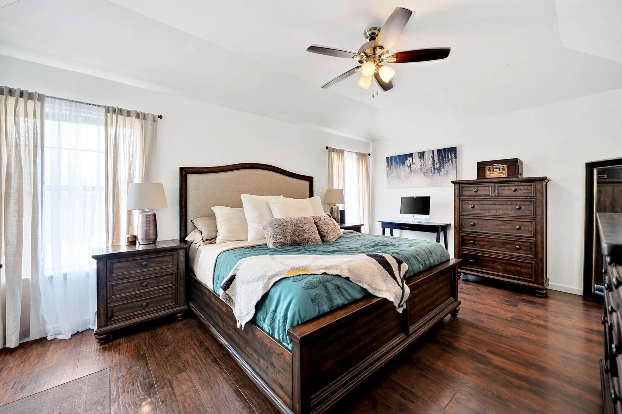 This remarkably spacious primary bedroom serves as a sun-drenched retreat, showcasing massive windows that look out over the private backyard.