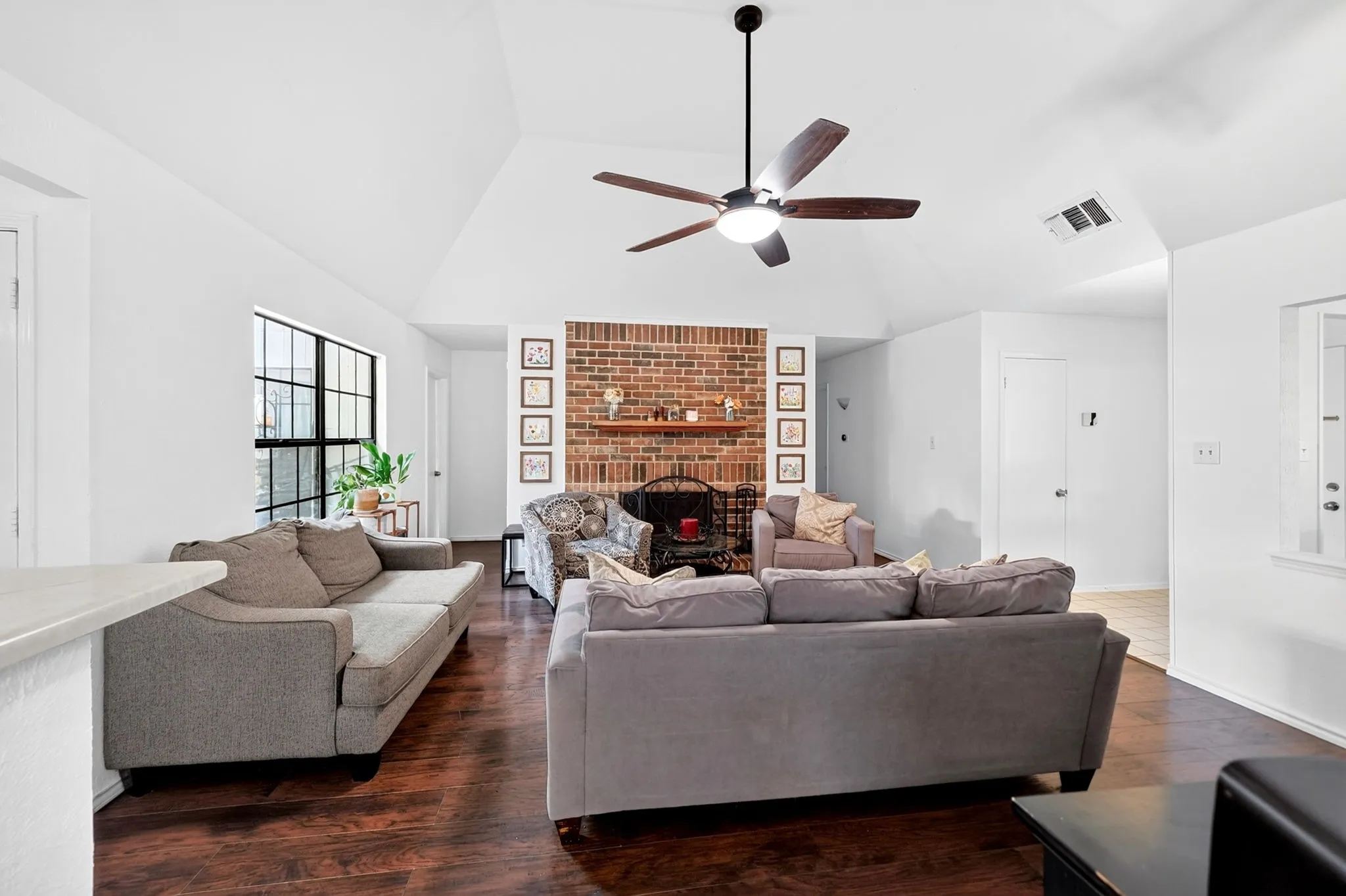 Freshly painted walls wrap the space in a clean, inviting glow while the charming, original brick fireplace adds rich texture.