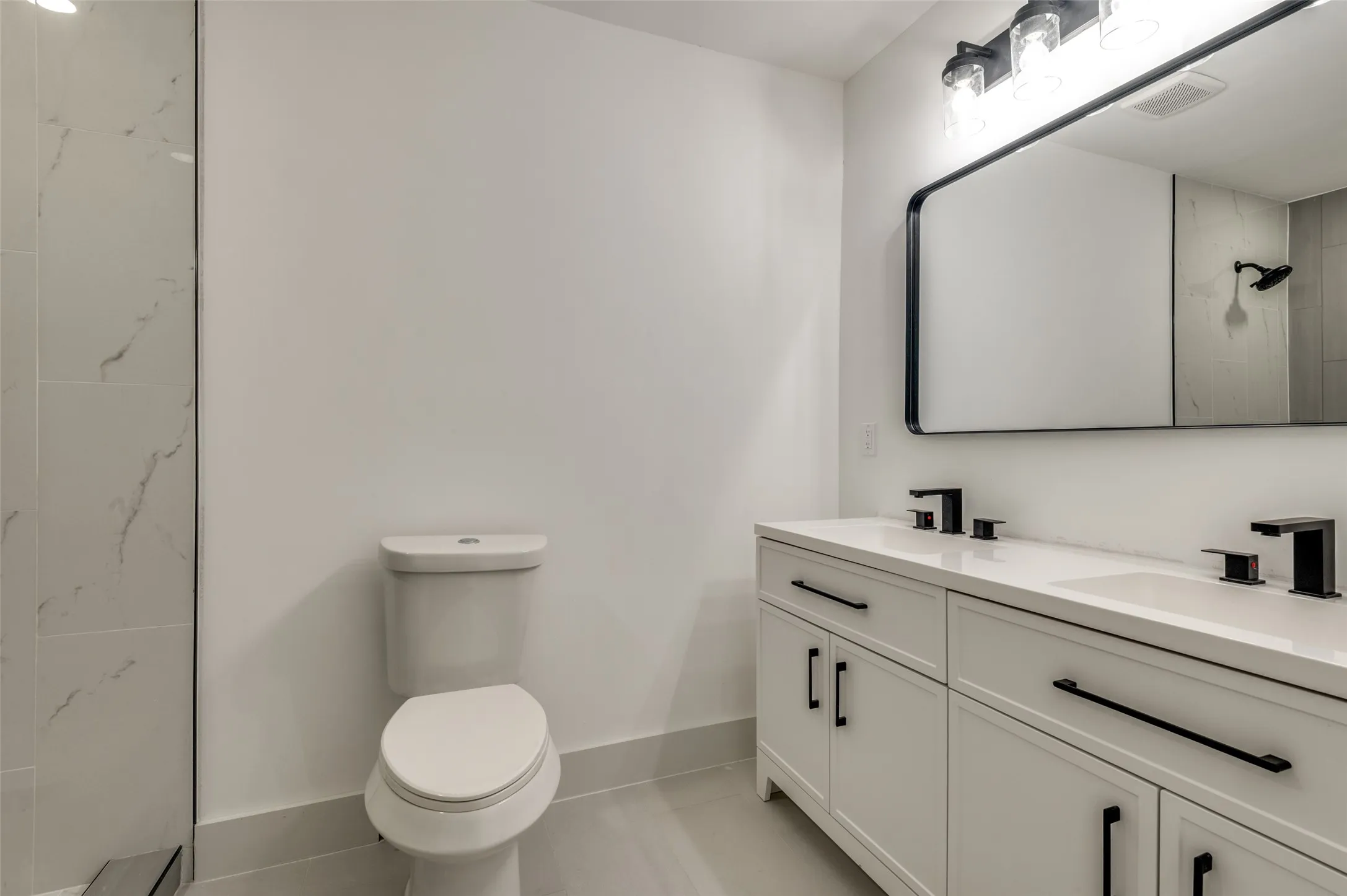 Bathroom featuring a double vanity with white cabinetry, integrated sinks, and black hardware