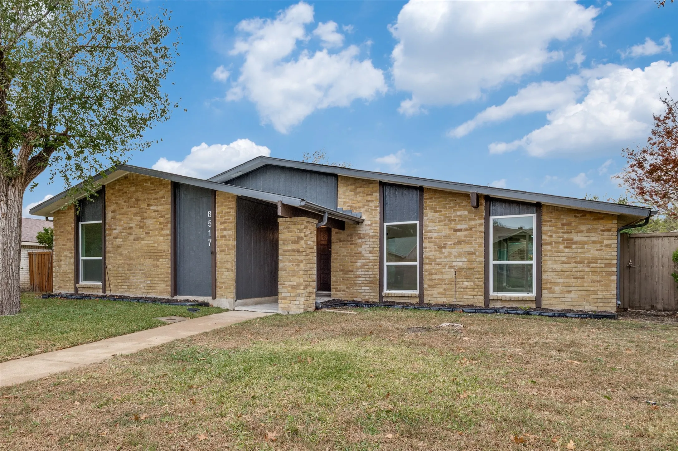 Mid-century modern exterior featuring a brick facade, prominent roofline, and front entry with numerical address