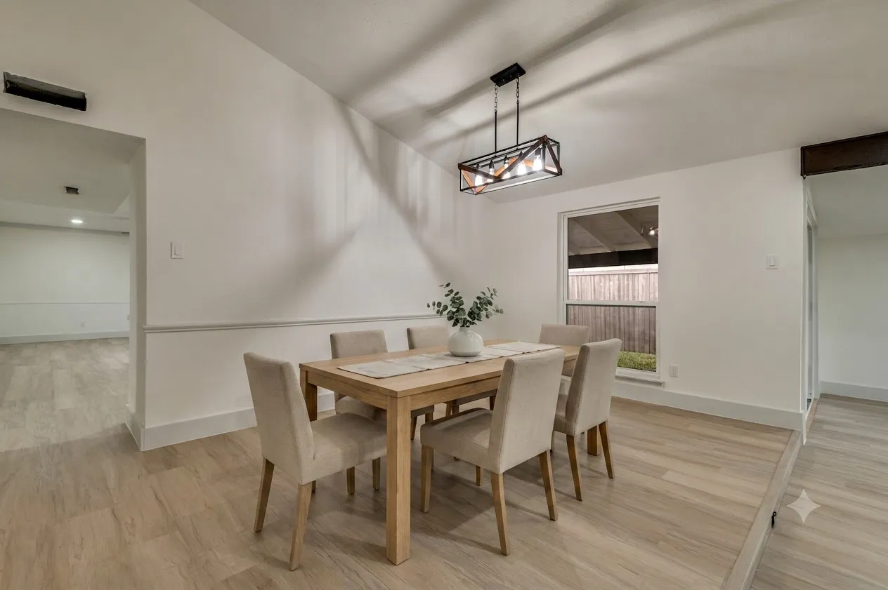 Virutally Staged Dining area featuring light wood-finish flooring, a contemporary linear chandelier, and a large window