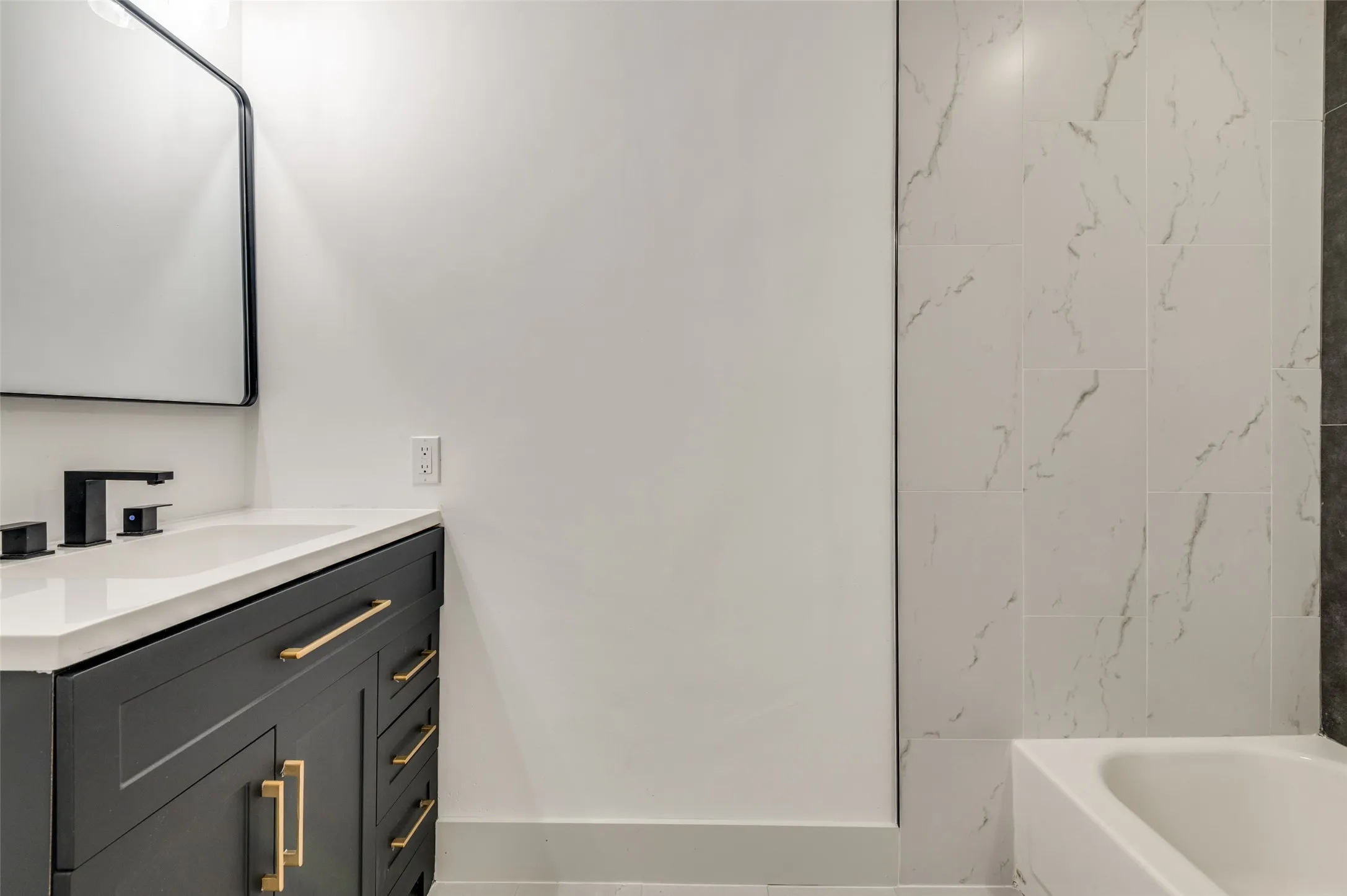 Dark gray vanity with gold-tone hardware, white countertop, and integrated sink