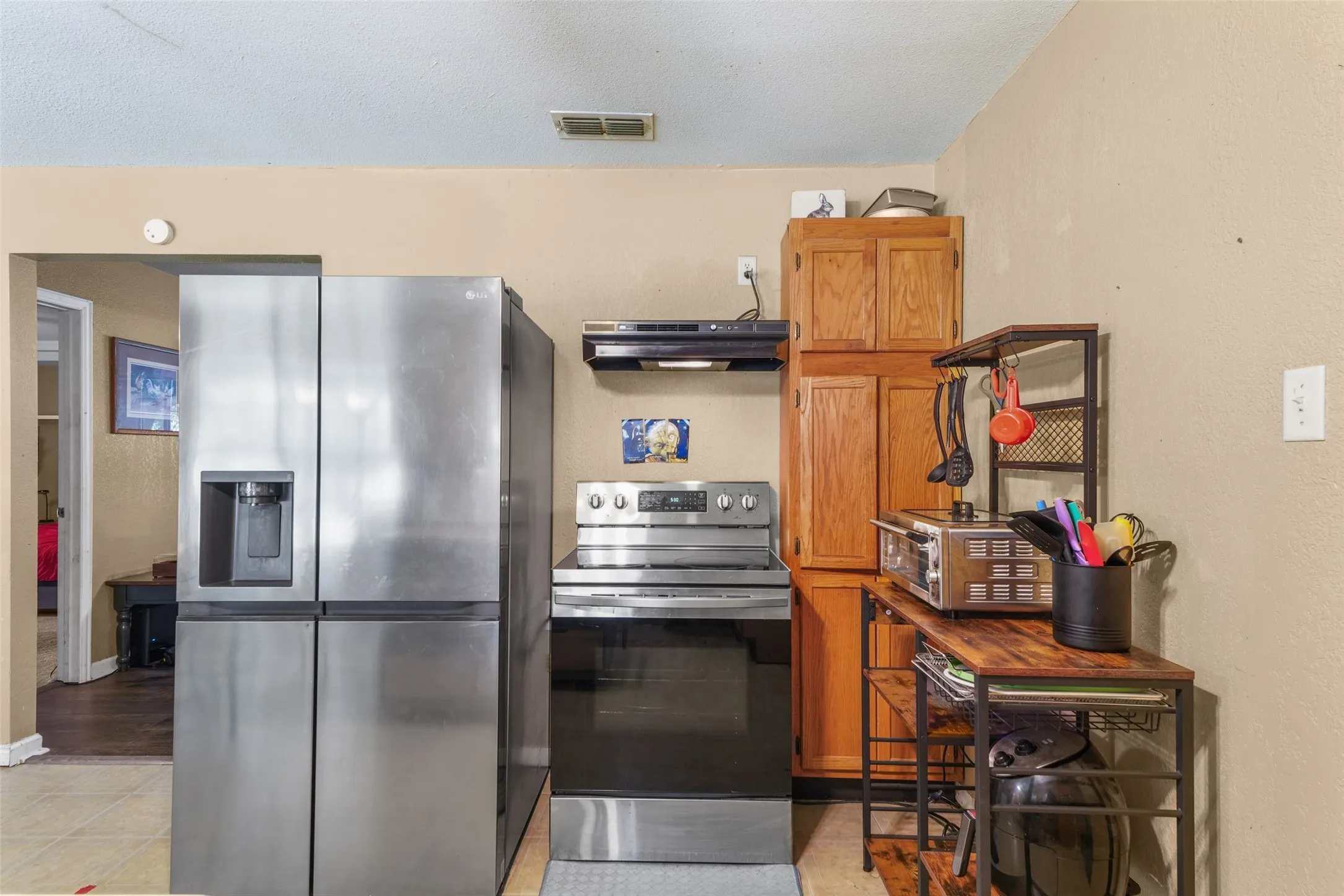 Kitchen featuring a stainless steel French door refrigerator with ice and water dispenser, a stainless steel range, and wood-finish cabinetry
