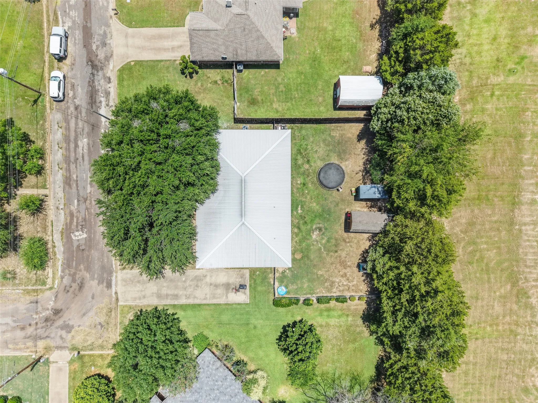 Aerial perspective showcasing a residential property with a shingle roof and a spacious backyard