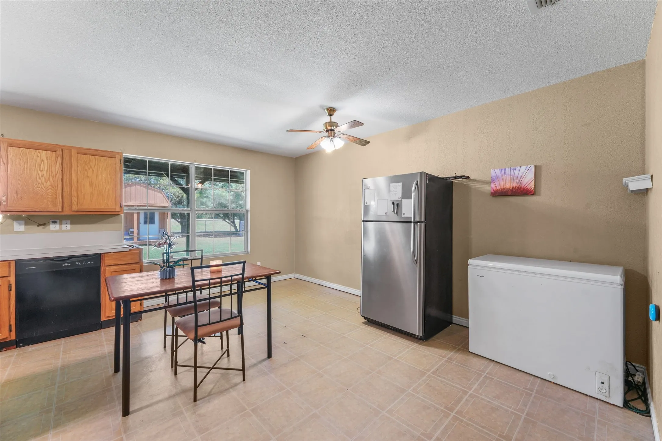Kitchen space featuring wood cabinetry, a built-in dishwasher, and tile flooring