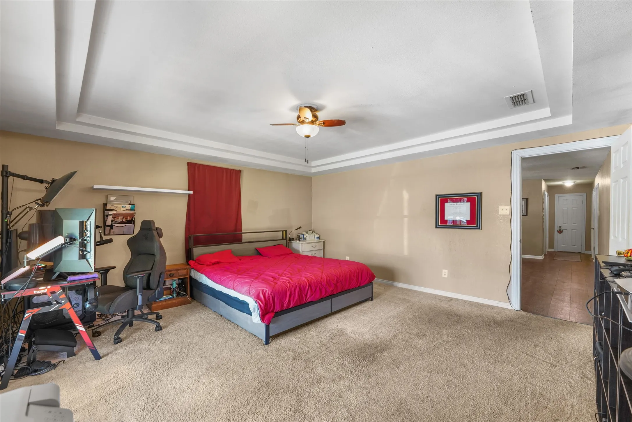 Spacious room featuring tray ceilings, neutral wall tones, and plush carpet flooring