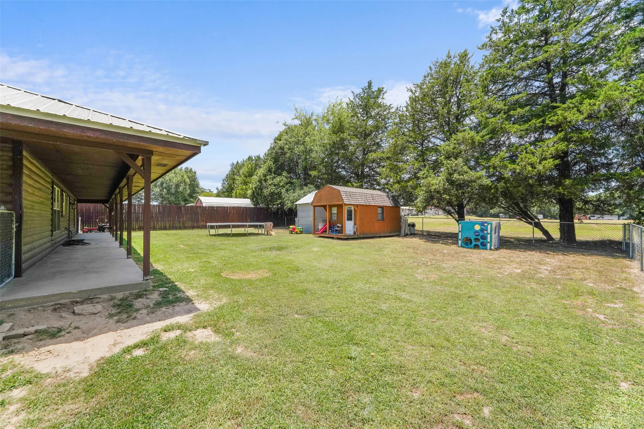 Aerial perspective showcasing the property with a metal-roofed structure, concrete patio, and mature trees