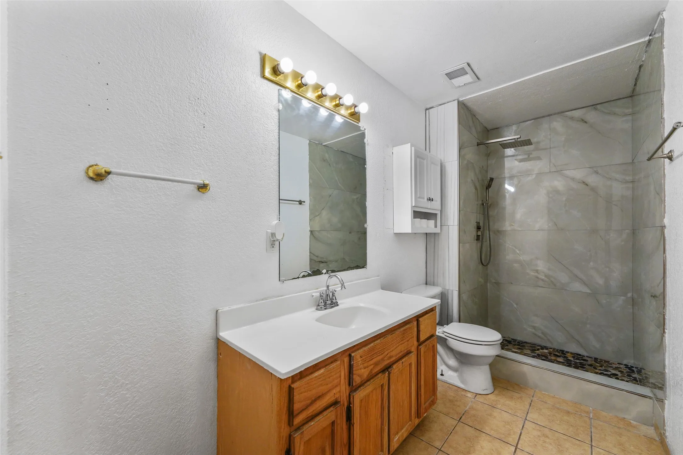Expansive backyard featuring a covered patio, a separate storage shed, perimeter fencing, and mature trees