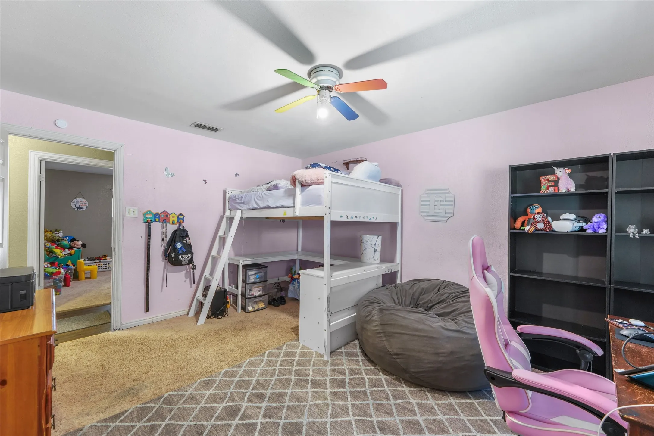 Carpeted interior room featuring a window with blinds, a ceiling fan with light fixture, and textured gray walls