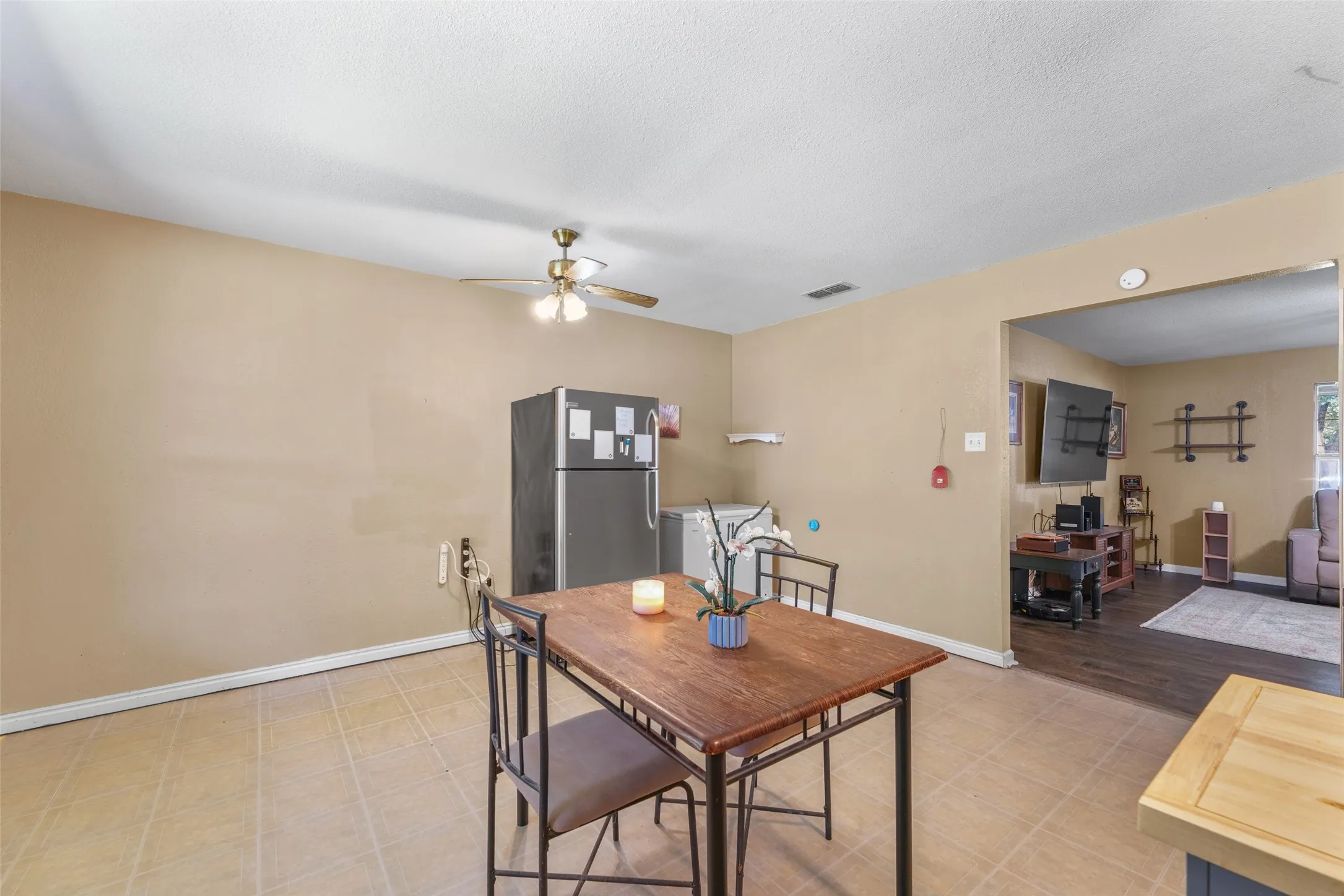 Spacious kitchen area featuring tile flooring, a ceiling fan with integrated lighting, and direct access to an additional living space