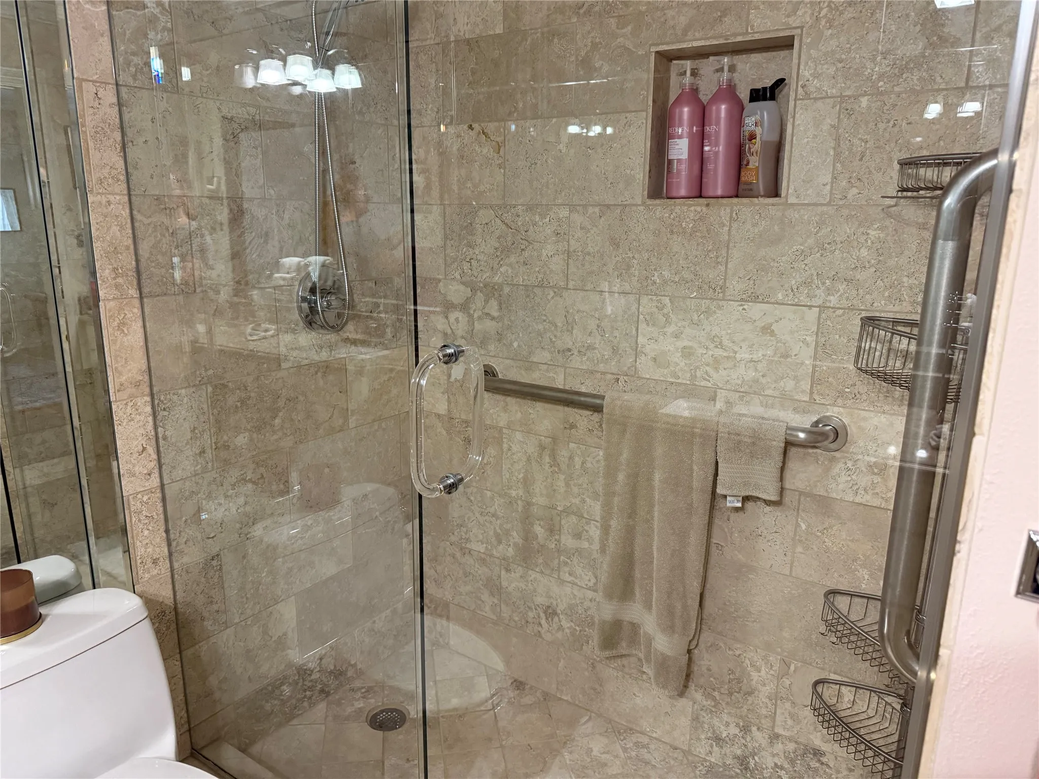 Glass-enclosed shower with stone-look tile surround