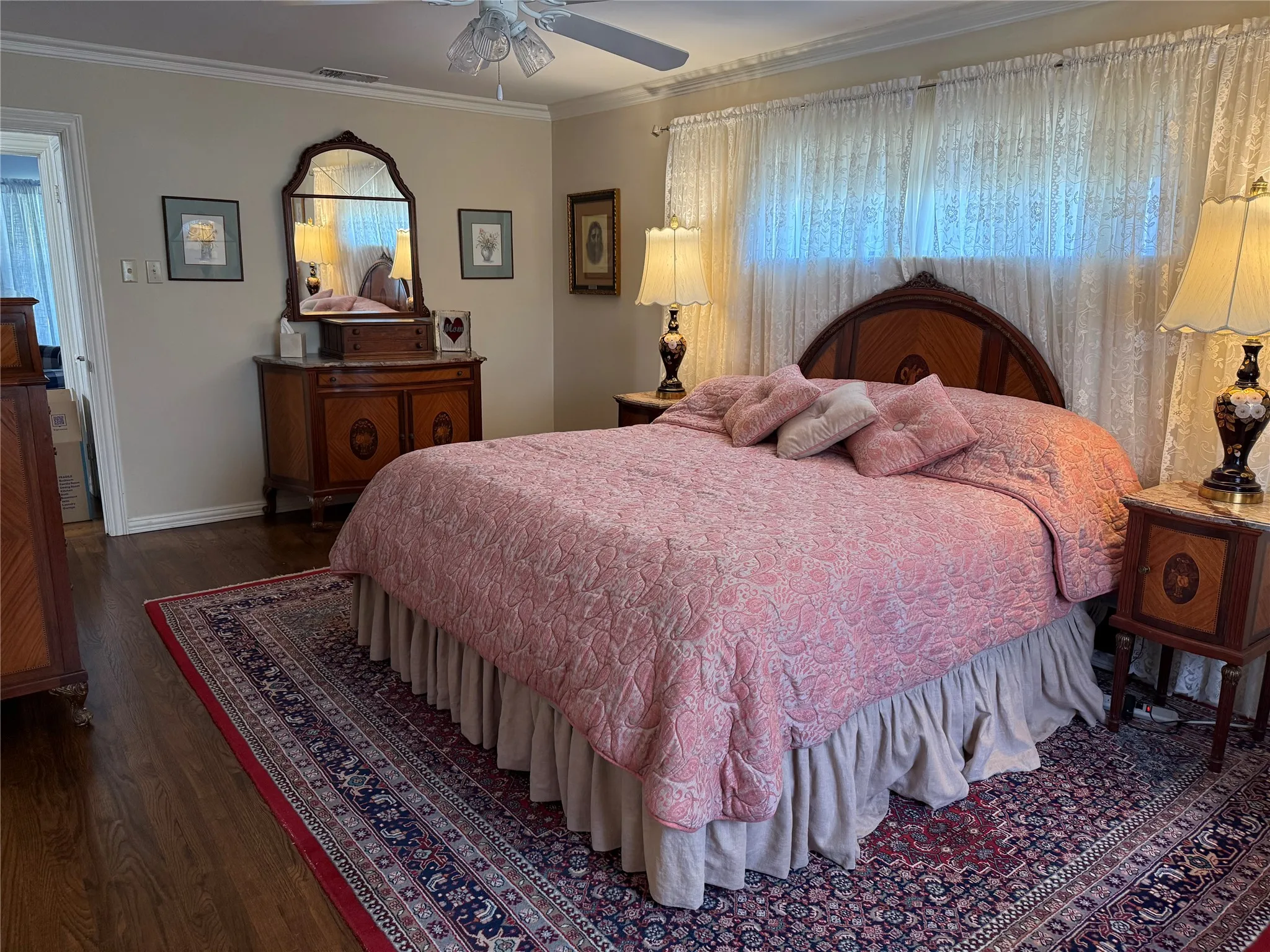Warm bedroom featuring wood-finish flooring, a decorative ceiling fan, and crown molding