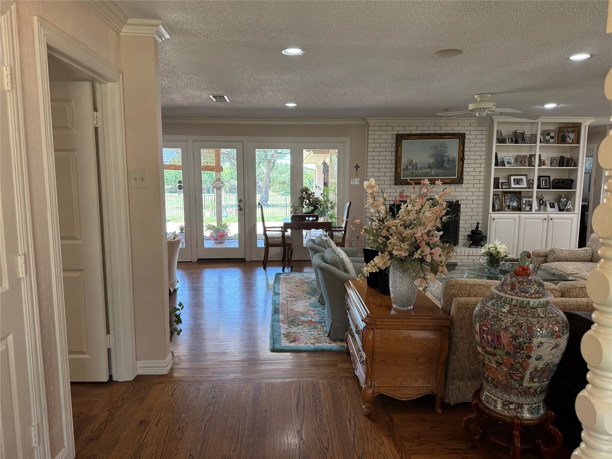 Living area with wood-finish flooring, recessed lighting, and a white brick fireplace