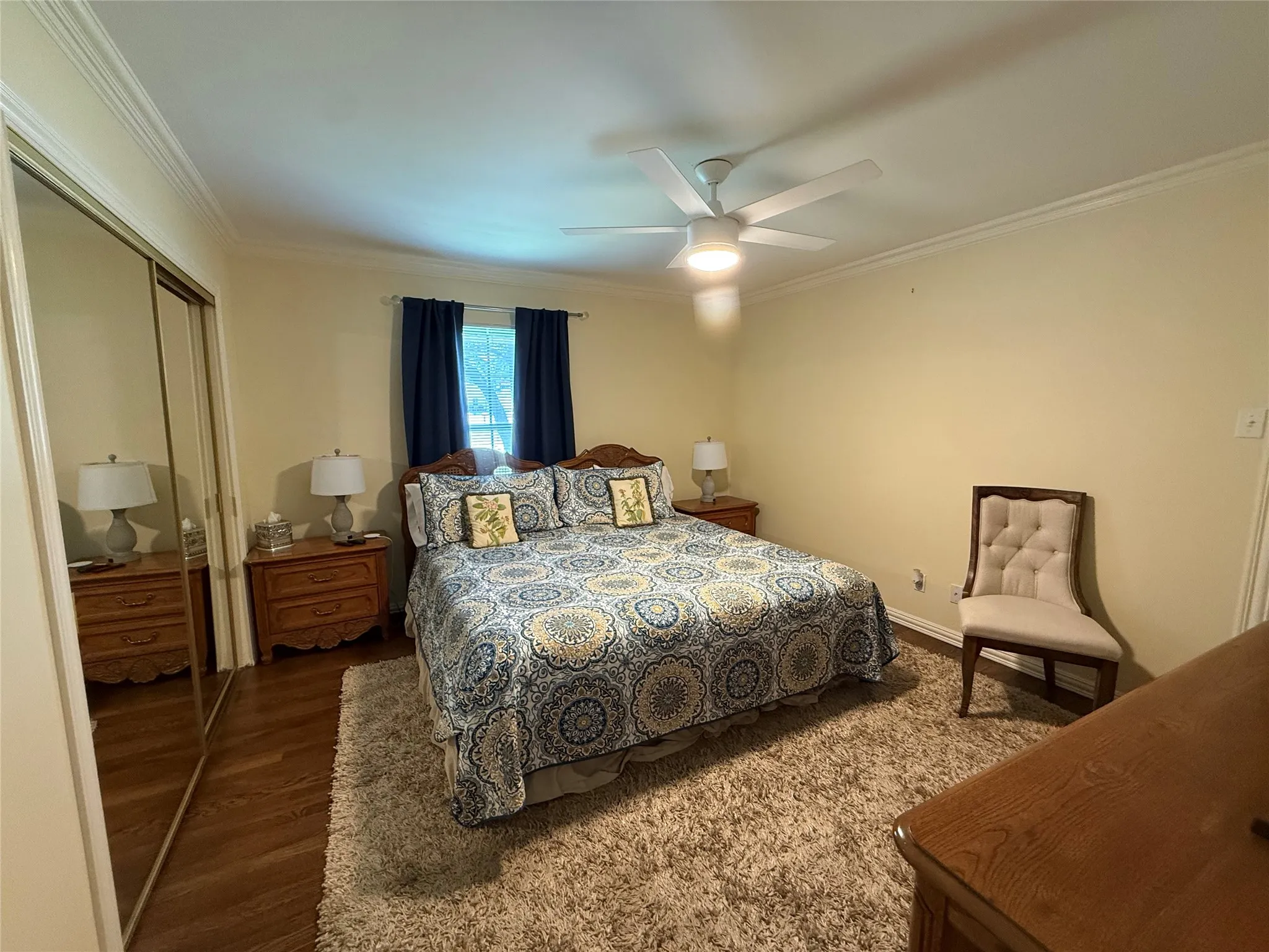 Bedroom featuring wood-finish flooring, a ceiling fan with integrated lighting, and crown molding