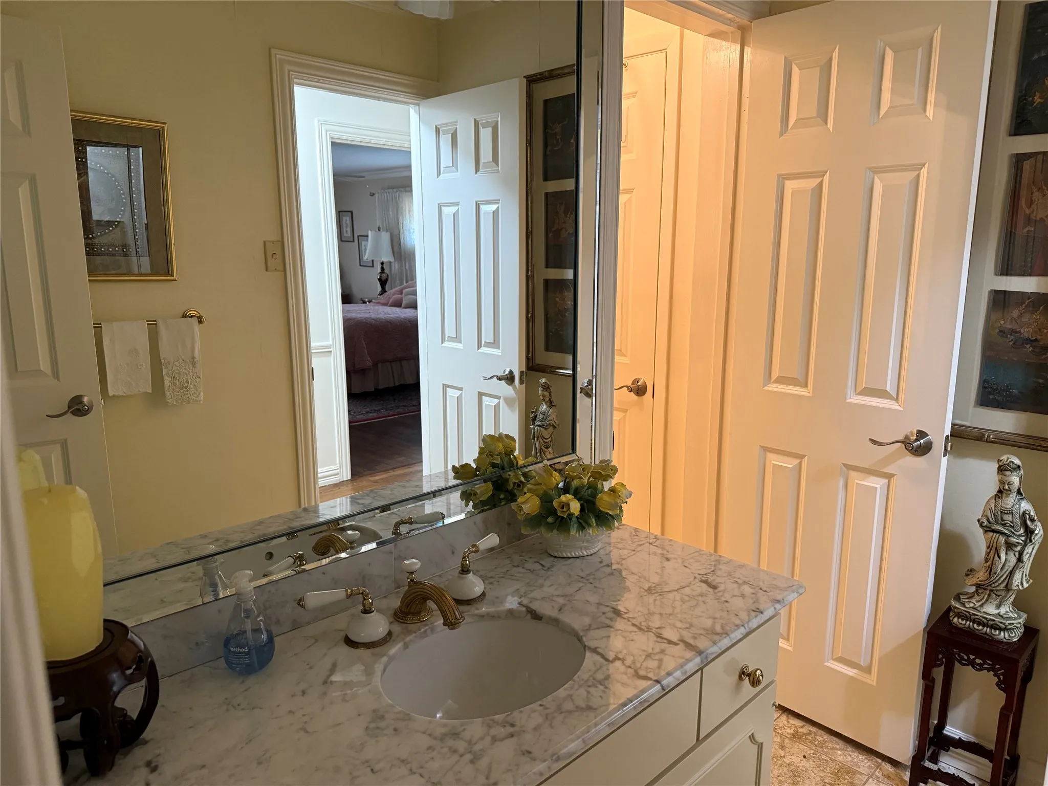 Bathroom vanity featuring a marble-finish countertop with an undermount sink and brass-tone fixtures