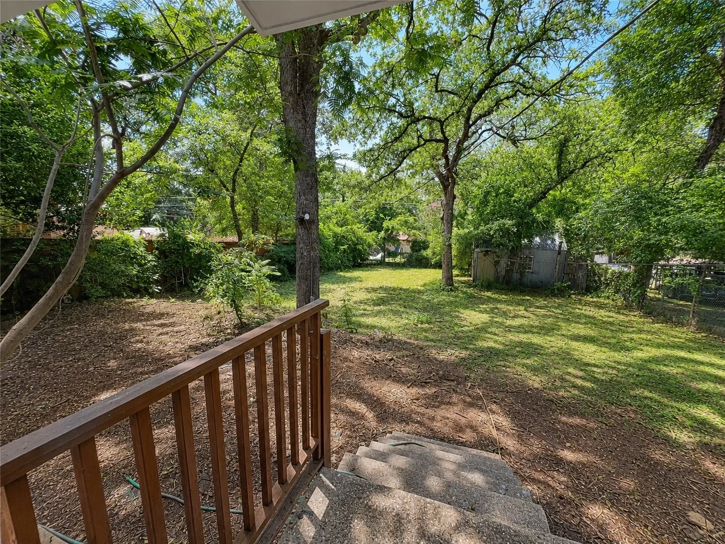Large back yard with high trees providing shadow the year round