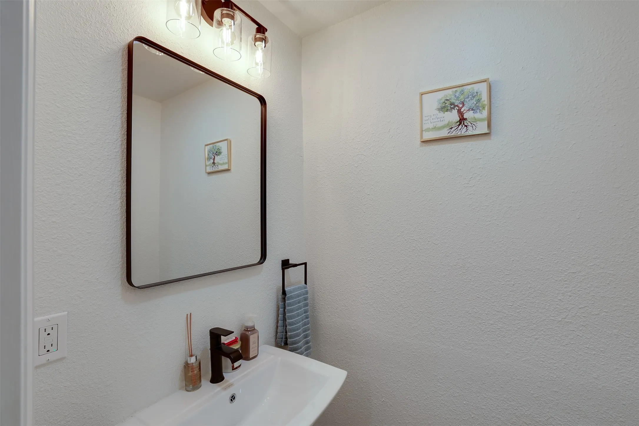 Contemporary vanity featuring a rectangular sink, matte black faucet, and a wall-mounted mirror with rounded corners