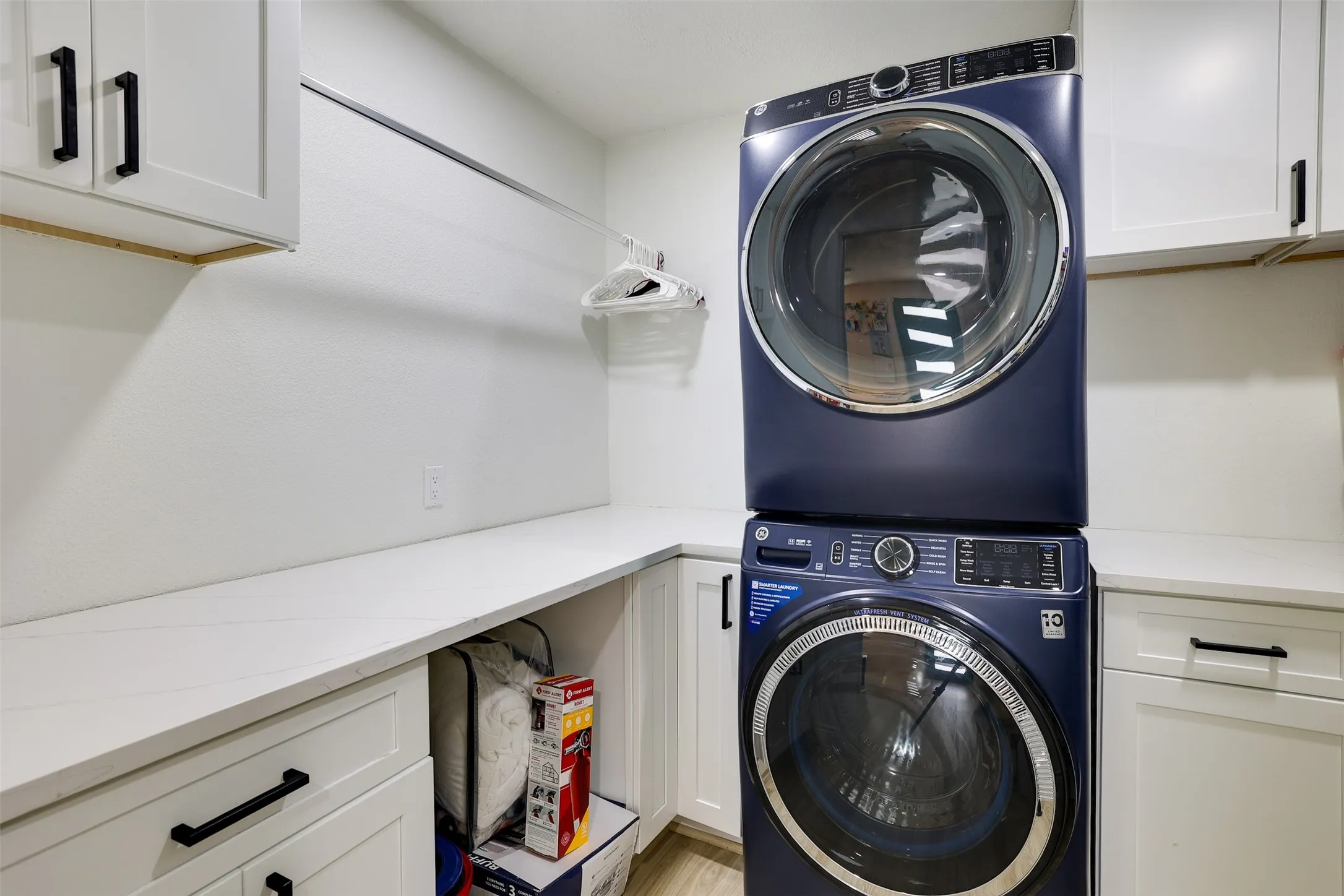Laundry space featuring white cabinetry, light countertops, and a clothes hanging rod