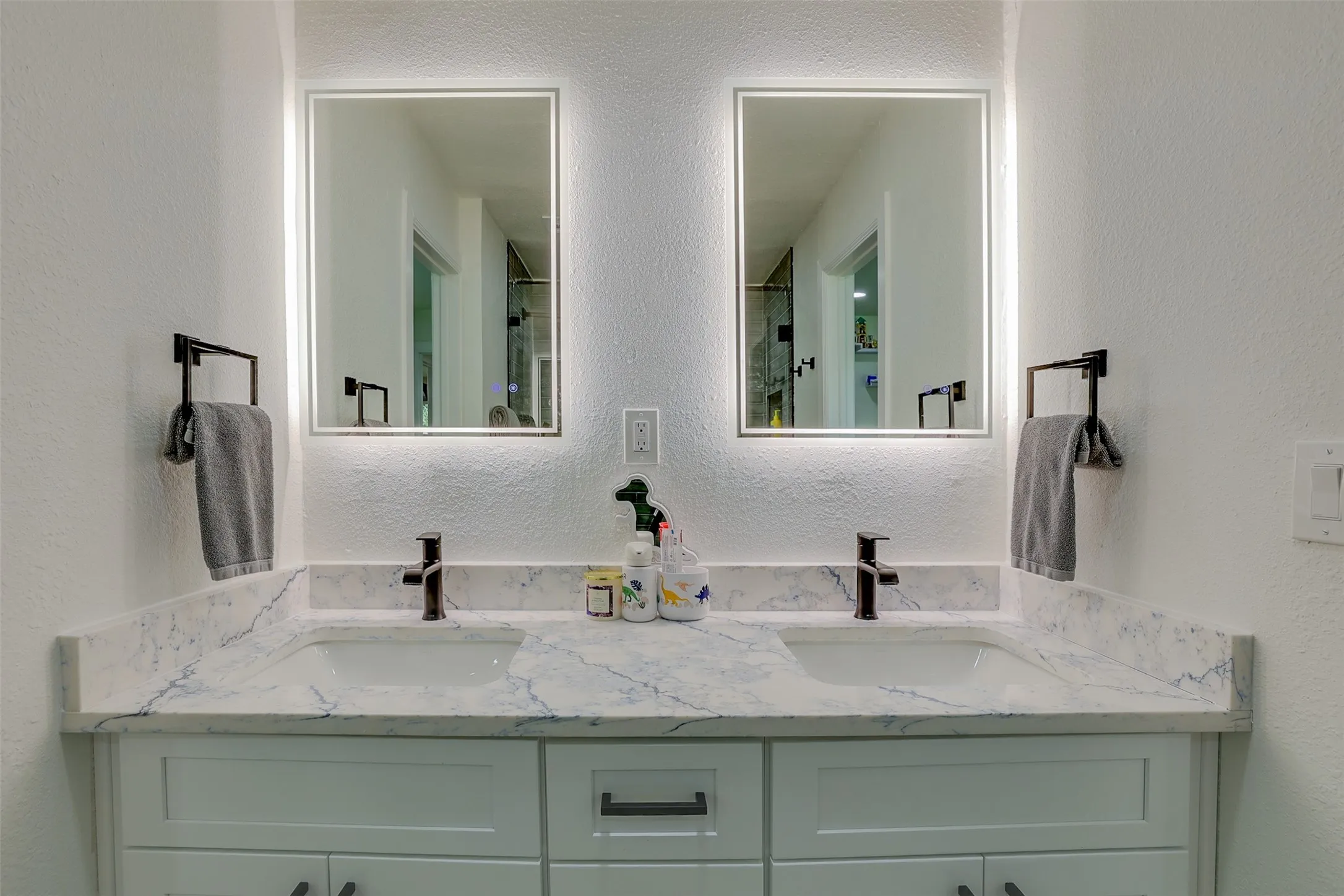 Double vanity with integrated sinks, a white and grey veined countertop, and contemporary black fixtures