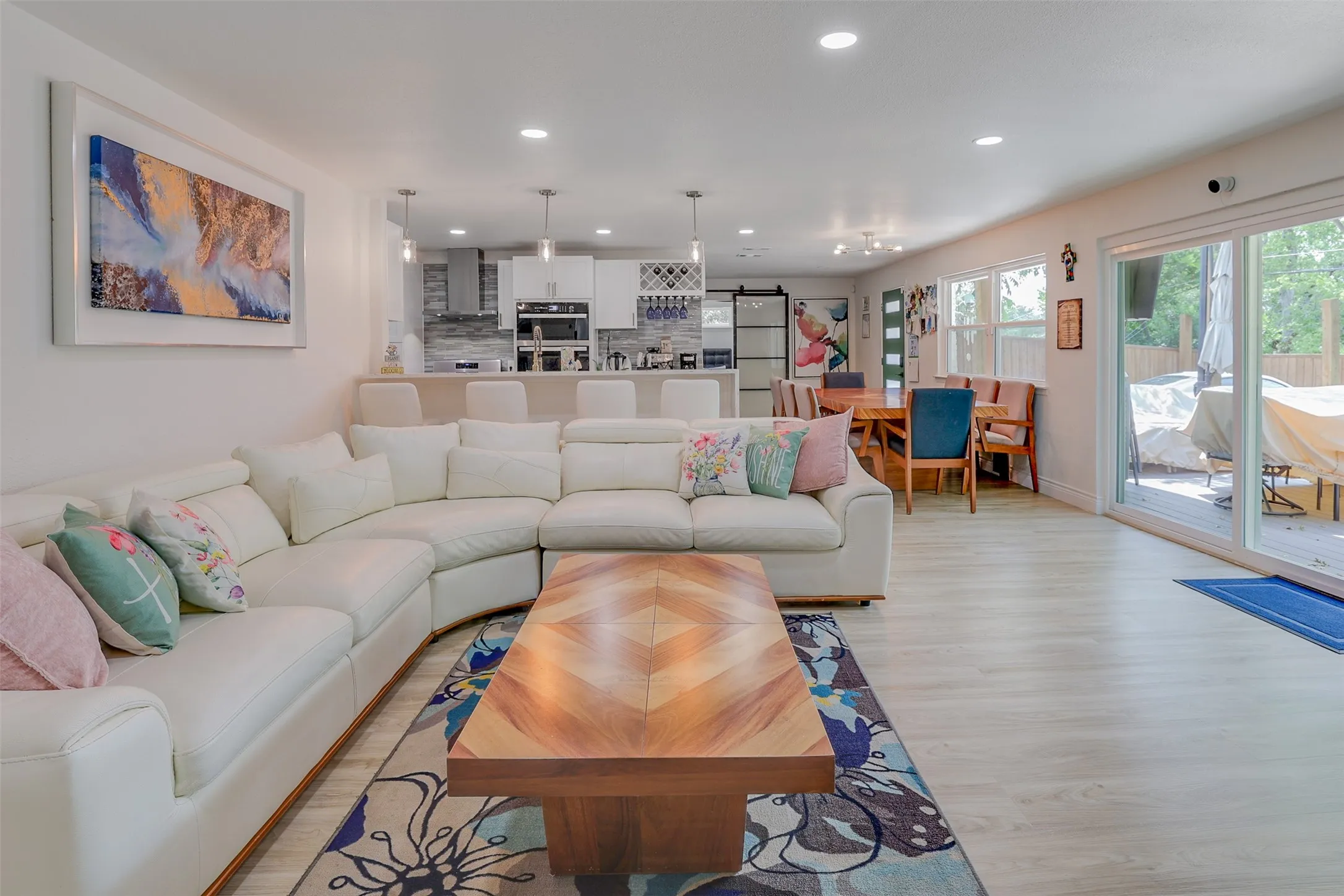 Open-concept living space featuring wood-finish flooring, recessed lighting, and sliding glass doors to the outdoor patio