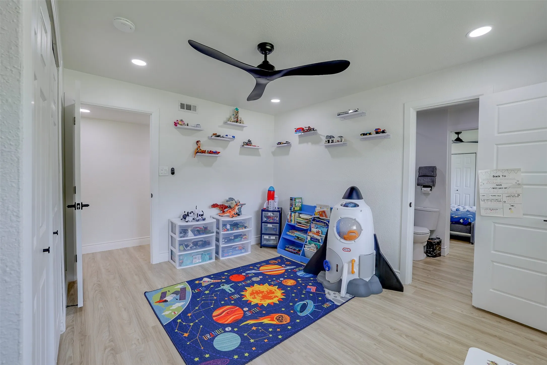 Bright room featuring light wood-finish flooring, recessed lighting, and a modern ceiling fan