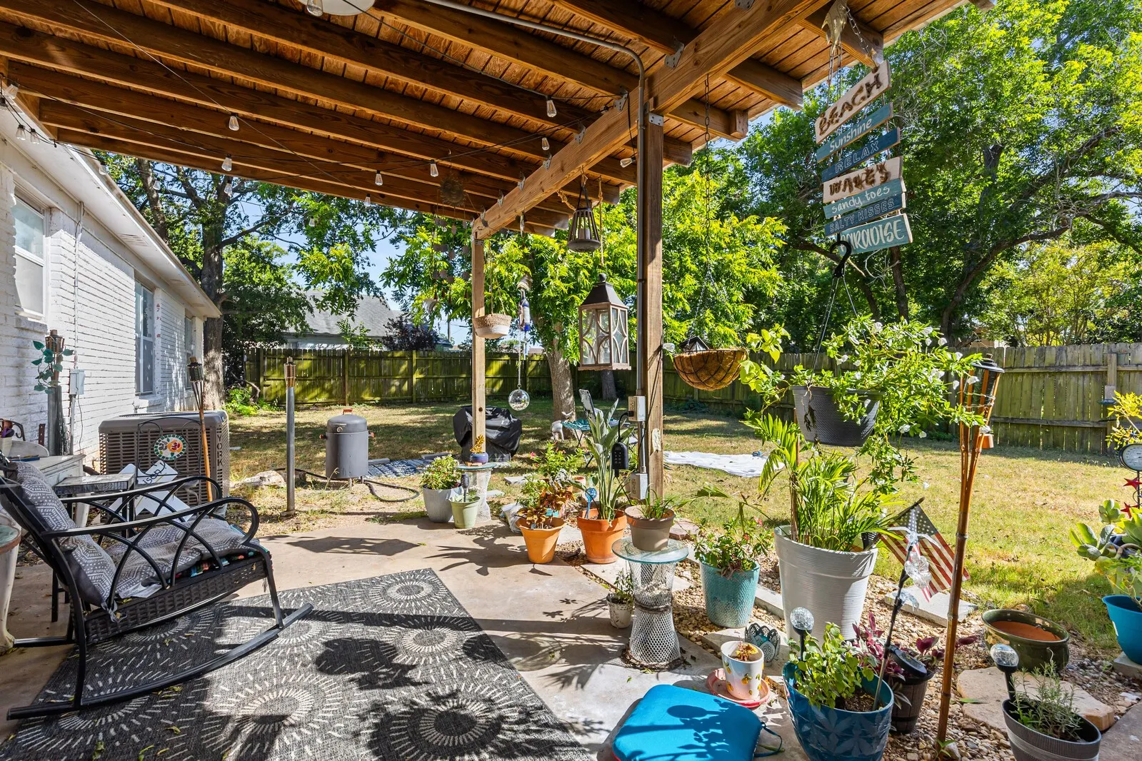 Covered patio with a wood-beam ceiling, concrete flooring, and string lighting