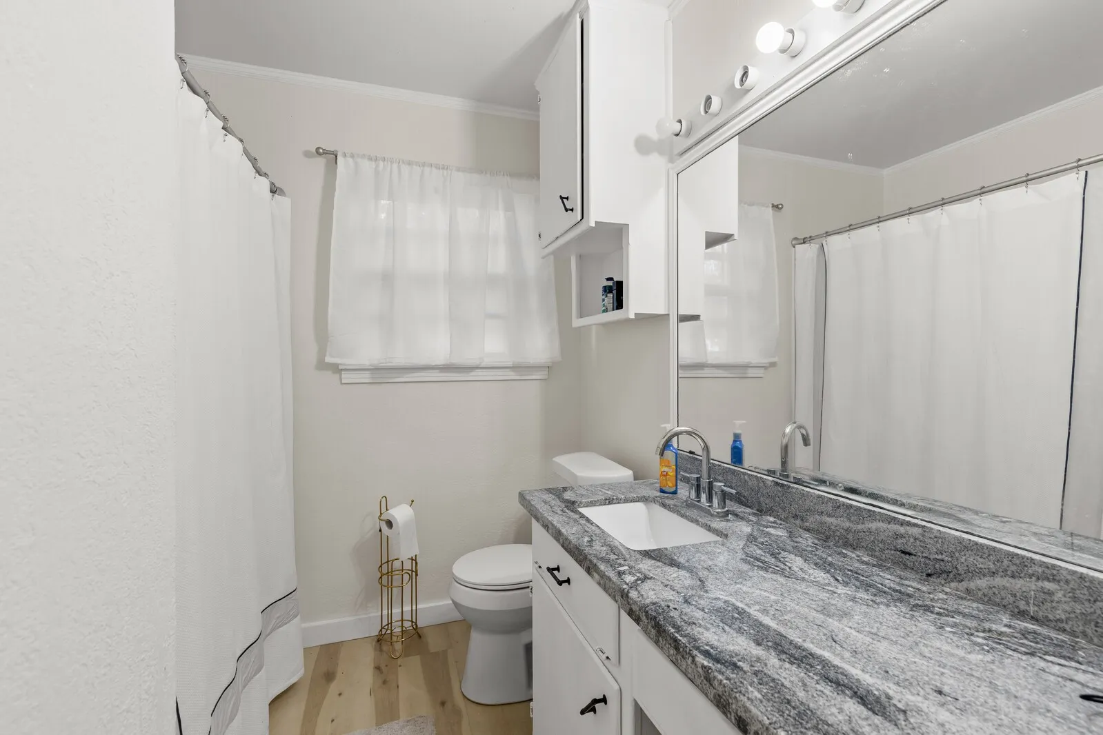 Bathroom featuring a vanity with a patterned countertop, a rectangular undermount sink, and polished chrome fixtures
