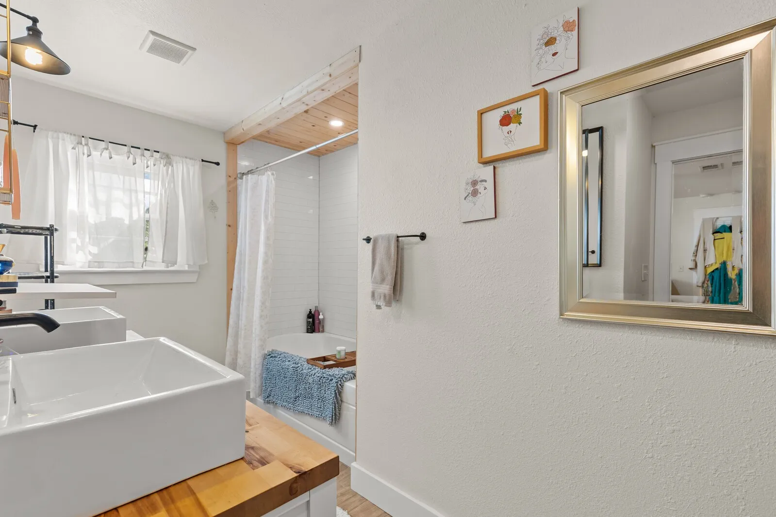 Bathroom featuring a double vanity with vessel sinks, wood-finish countertop, and matte black fixtures