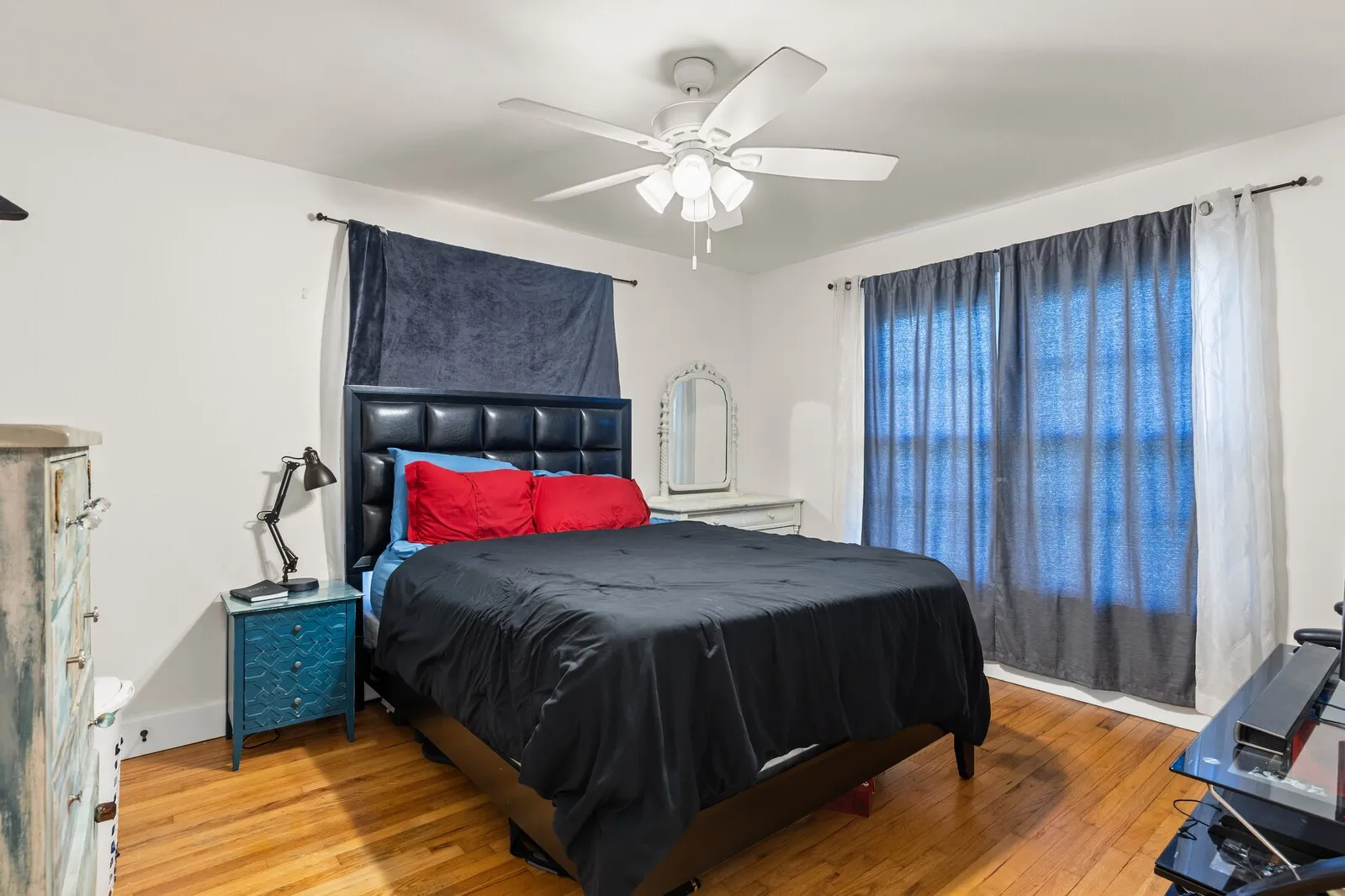 Room featuring hardwood flooring, white walls, and a ceiling fan with integrated lighting