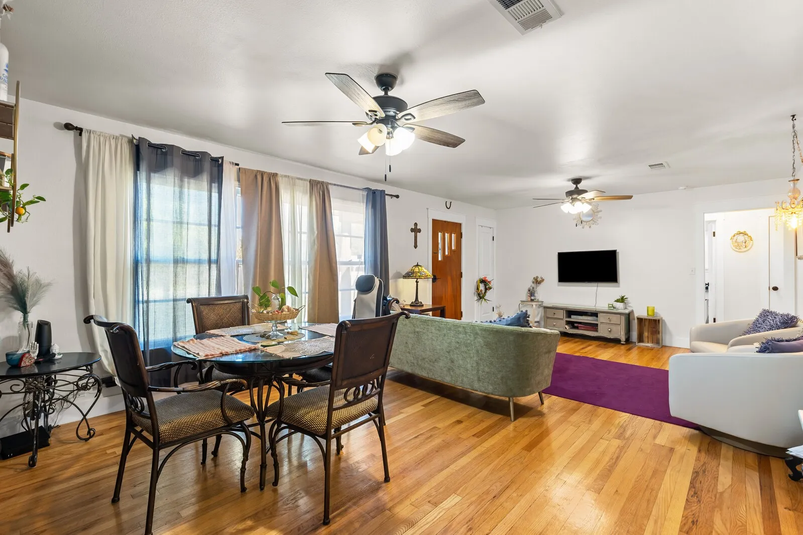Hardwood flooring spans the open-concept living area, featuring multiple ceiling fans with integrated lighting
