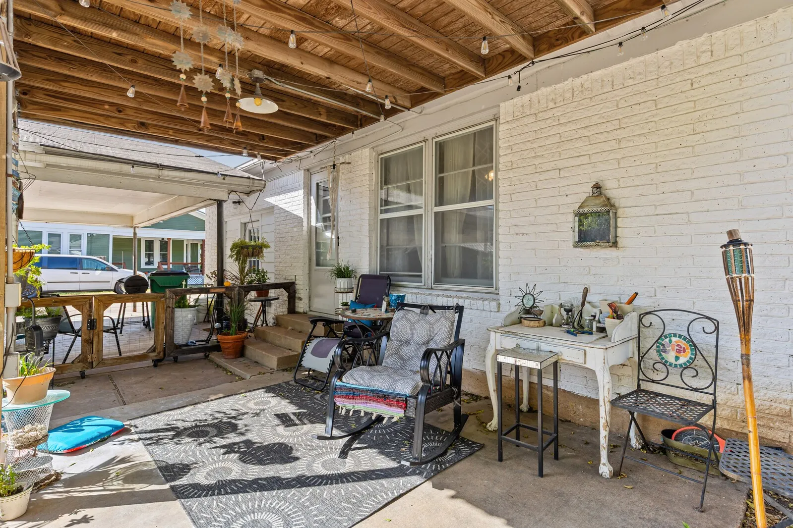 Covered patio featuring a wood-finish ceiling, exposed beams, and string lighting