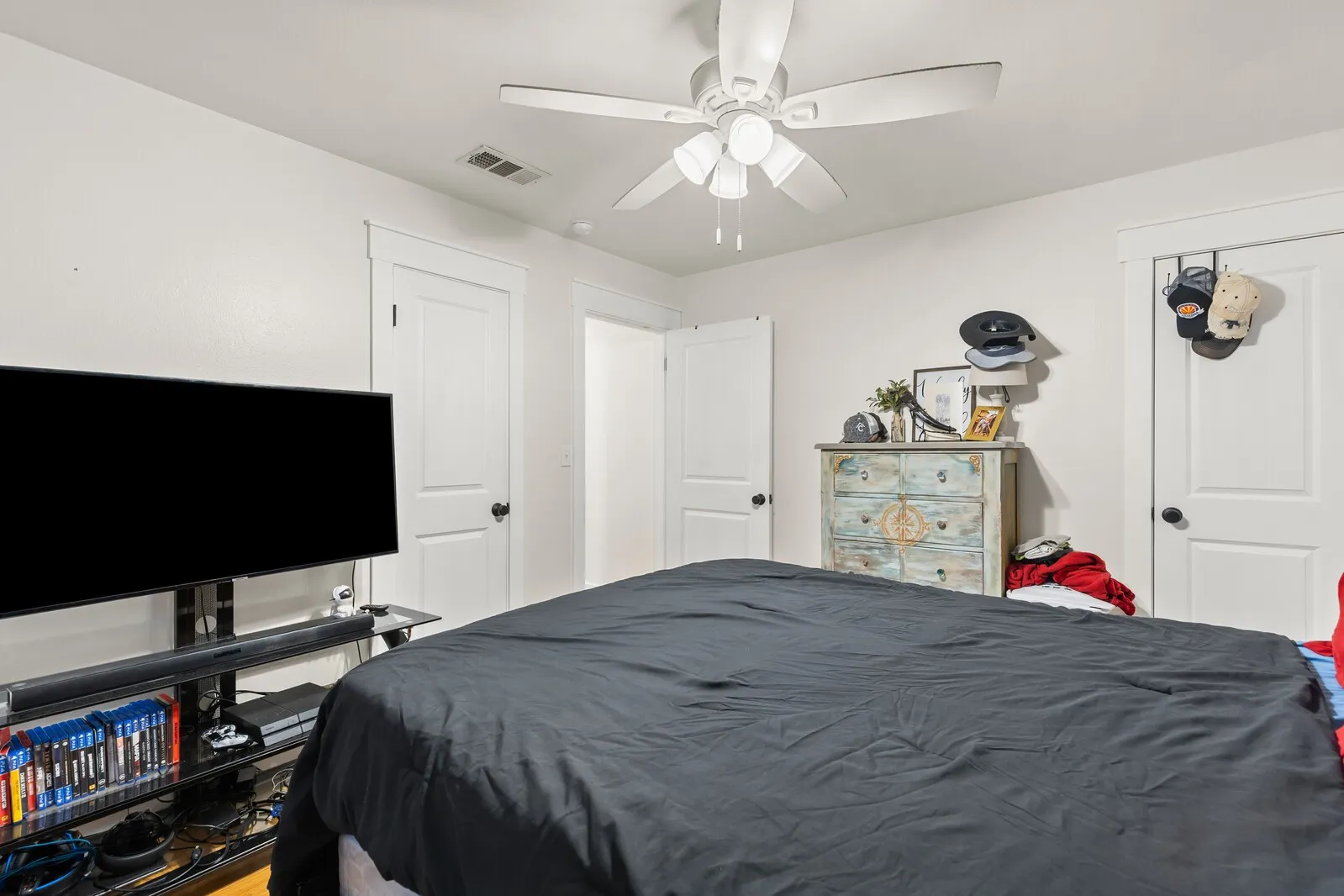 Recessed lighting and a ceiling fan fixture illuminate this bedroom, featuring white walls and white trim