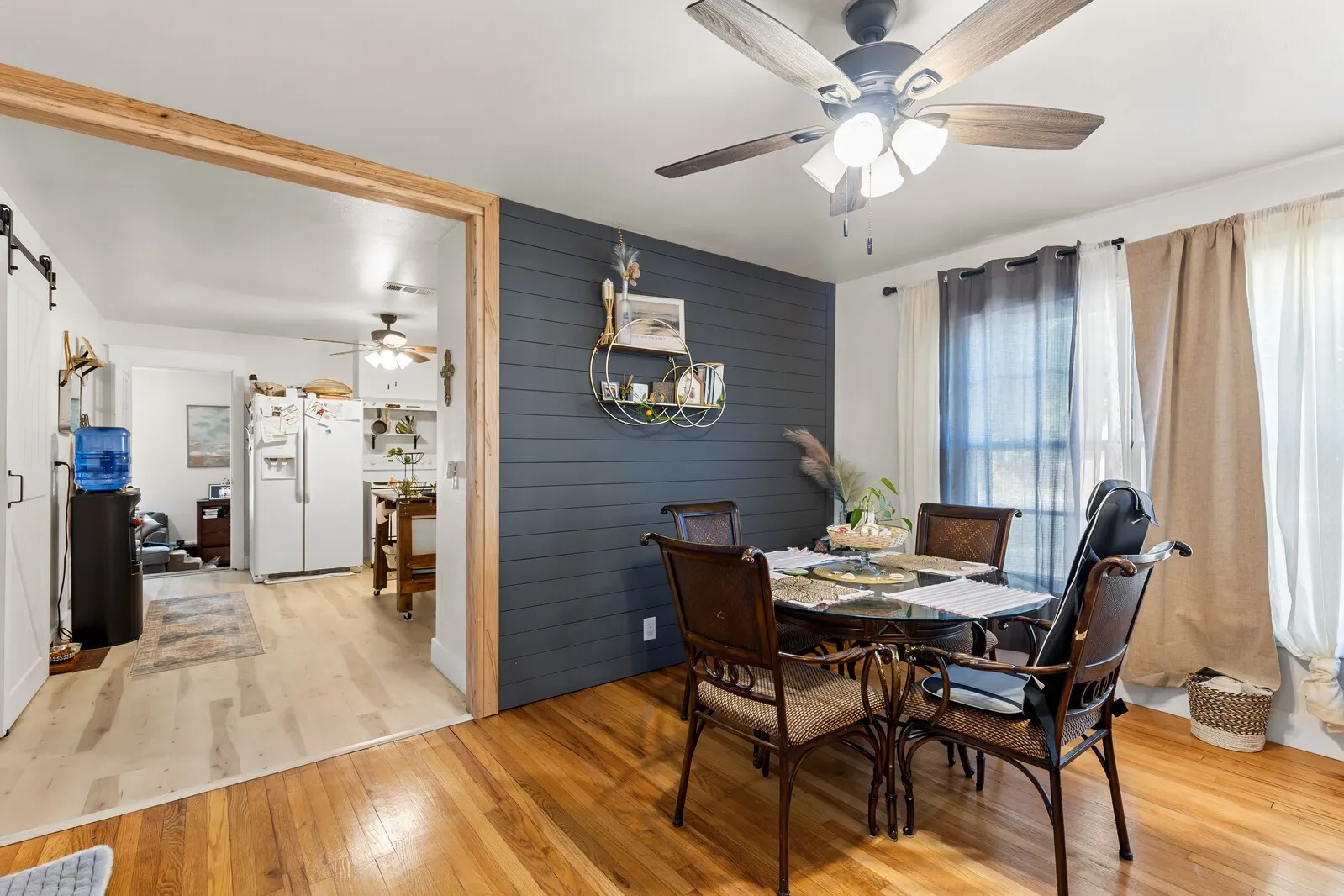 Dining area featuring a dark blue shiplap accent wall, wood-finish flooring, and a ceiling fan with integrated lighting