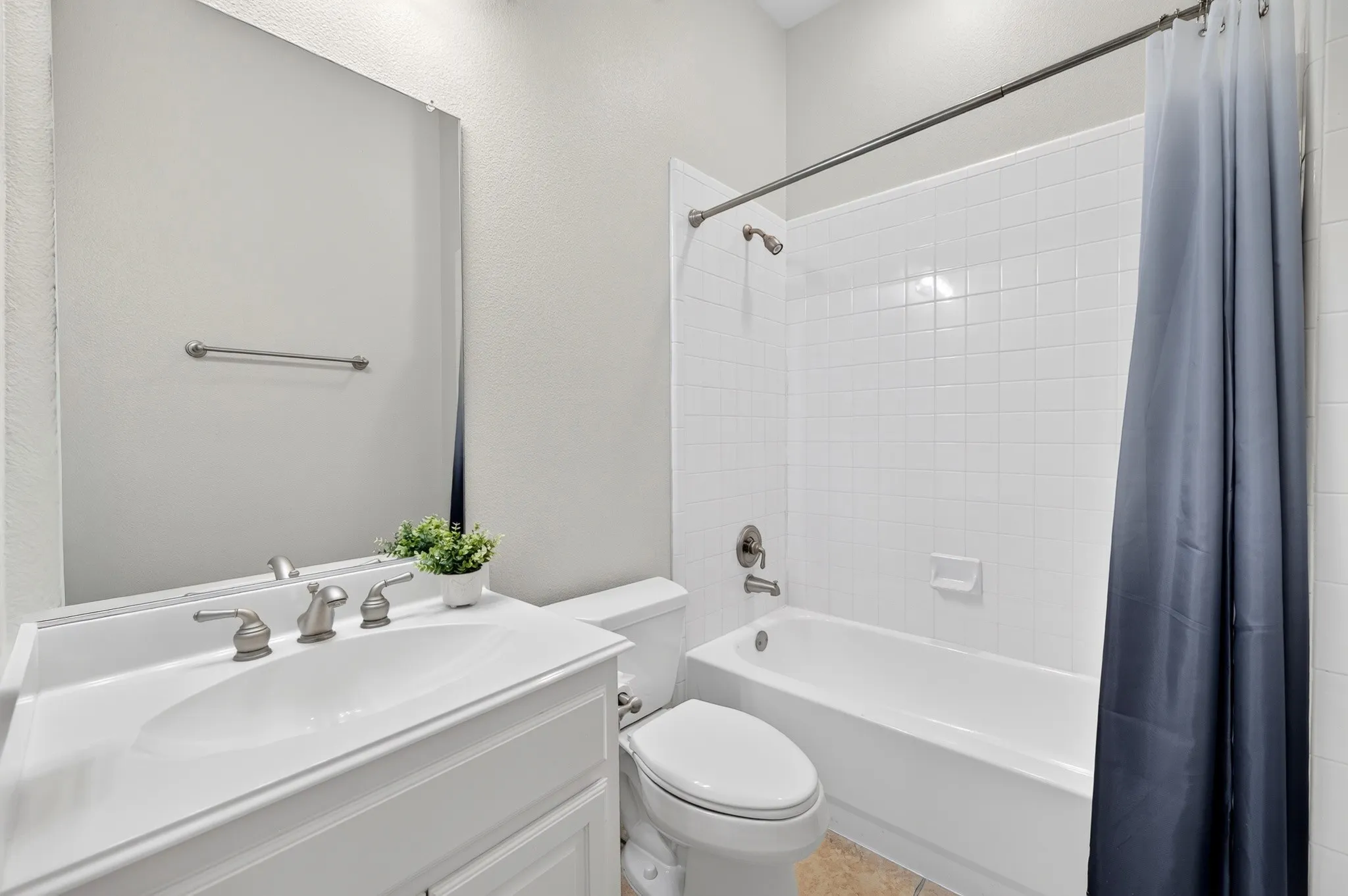 Bathroom featuring a white vanity with integrated sink, brushed nickel faucet, large wall mirror, and a tiled shower/tub combination
