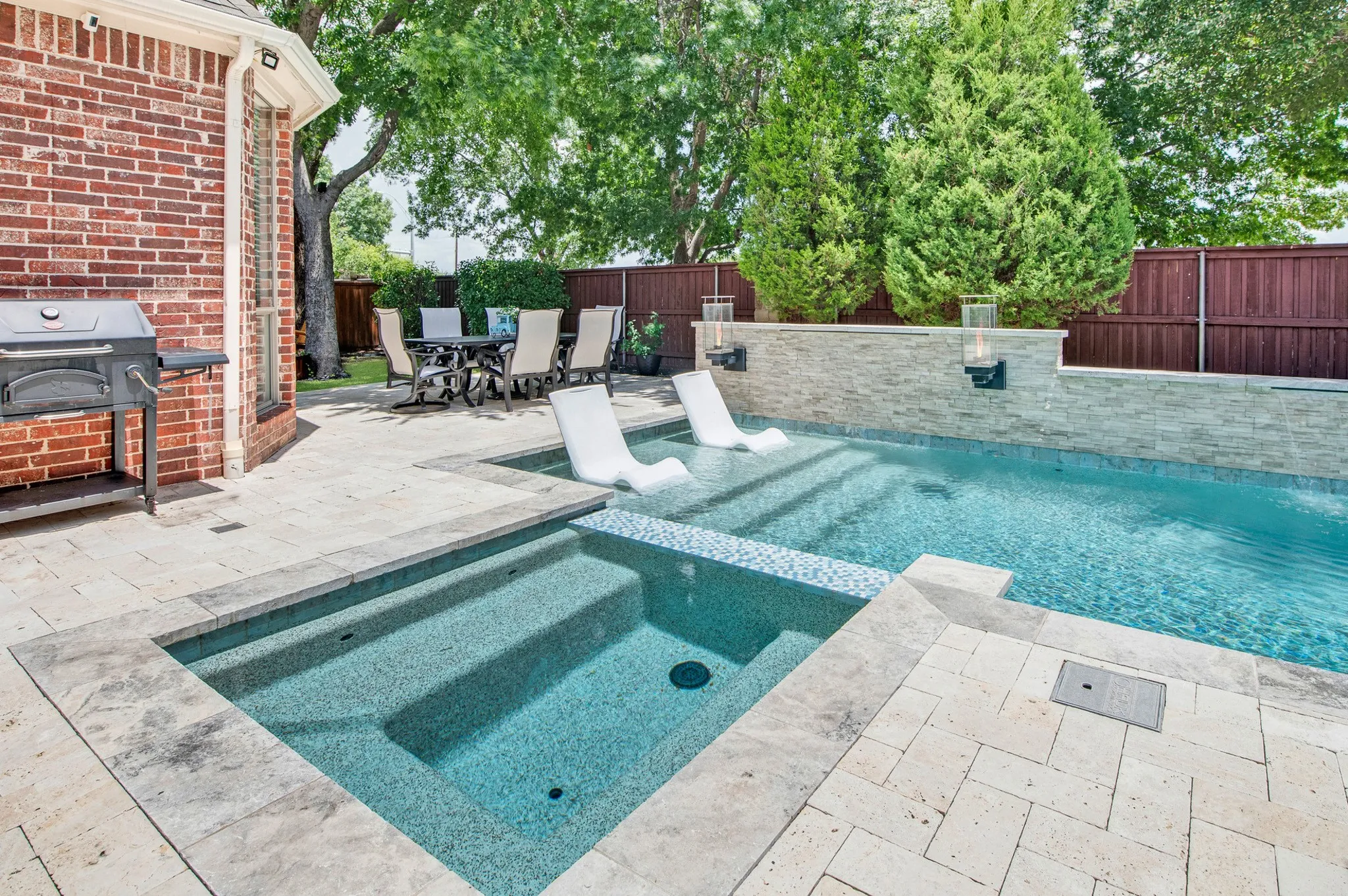 Outdoor living space featuring a custom-shaped pool, integrated spa, and an expansive paver patio