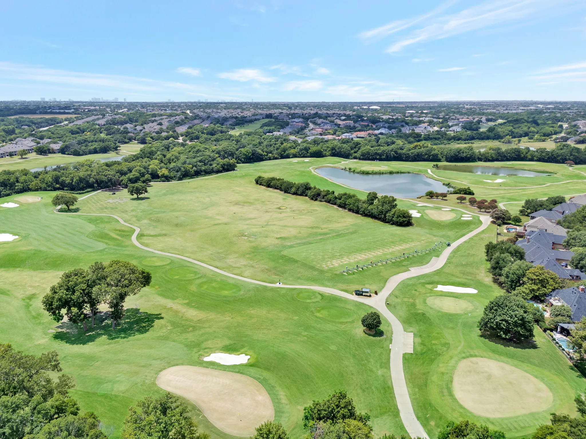 Expansive golf course setting featuring manicured greens, sand traps, and mature trees