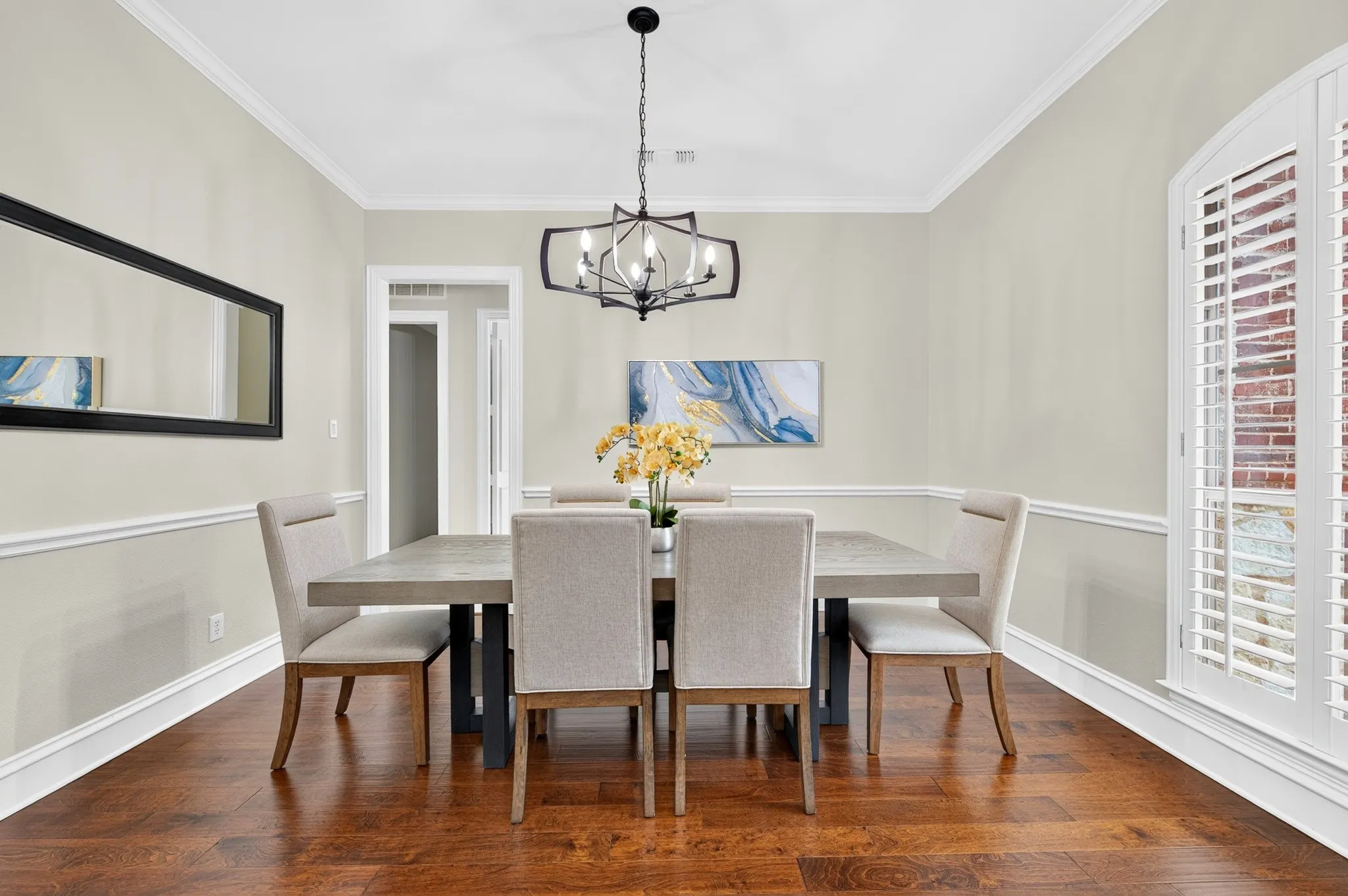 Formal dining space featuring rich wood-finish flooring, white crown molding, and wainscoting