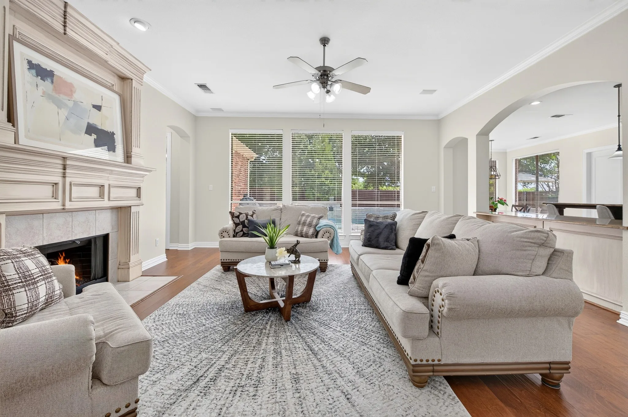 Spacious living area featuring wood-finish flooring, a ceiling fan, and large windows