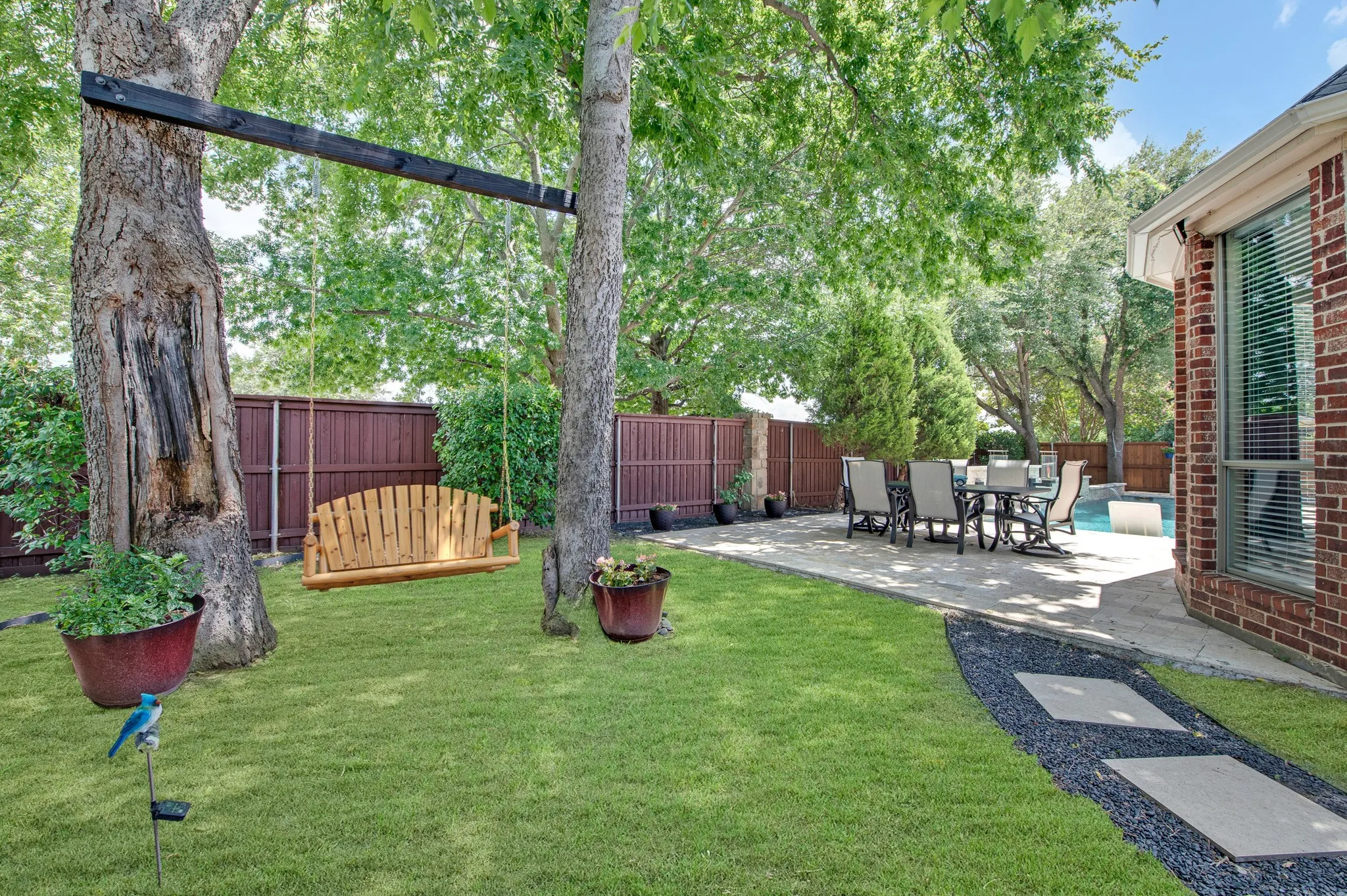 Expansive backyard featuring a manicured lawn, established trees, and privacy fencing