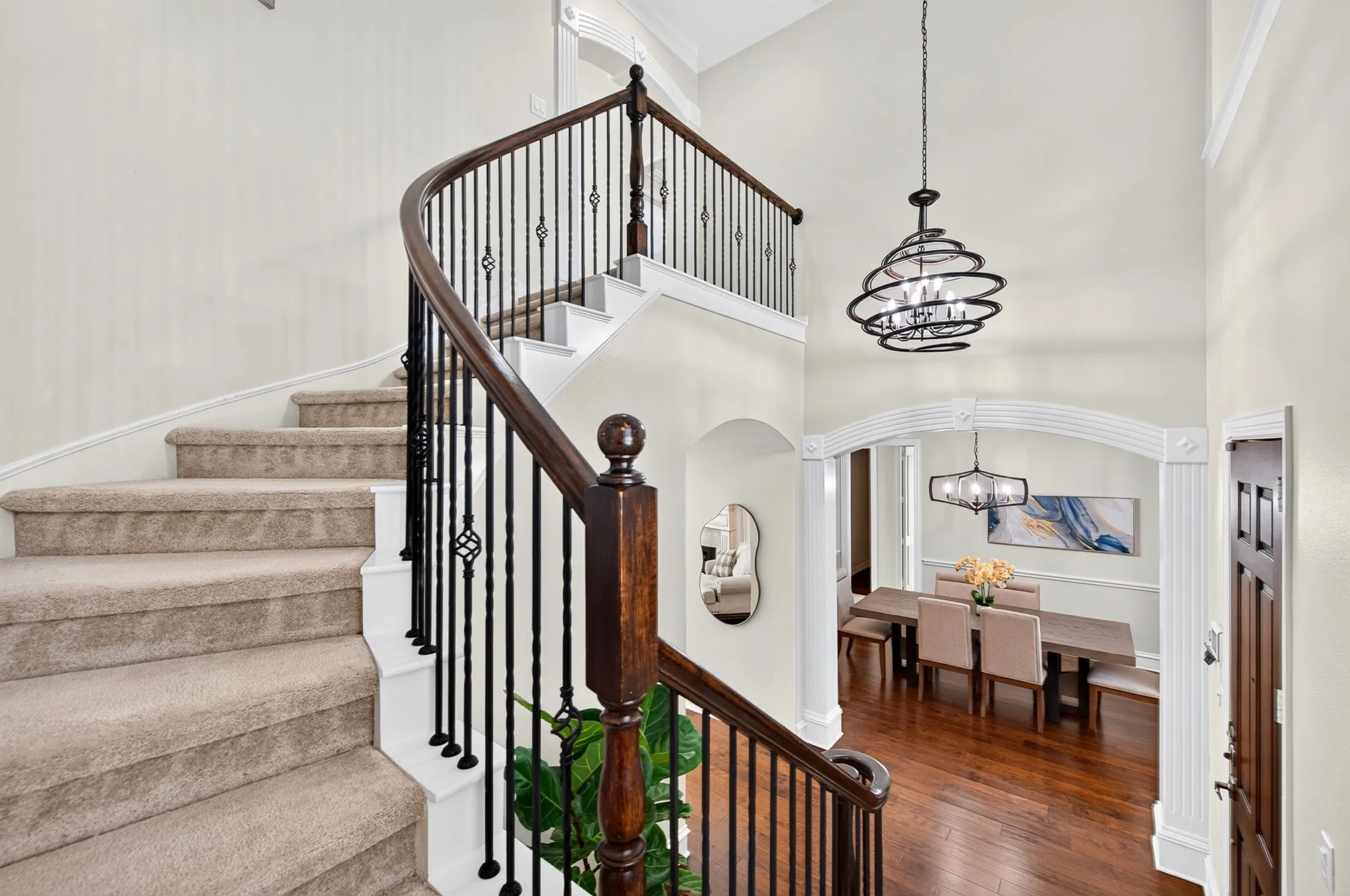 Grand curved staircase with wood newel posts and wrought iron balusters