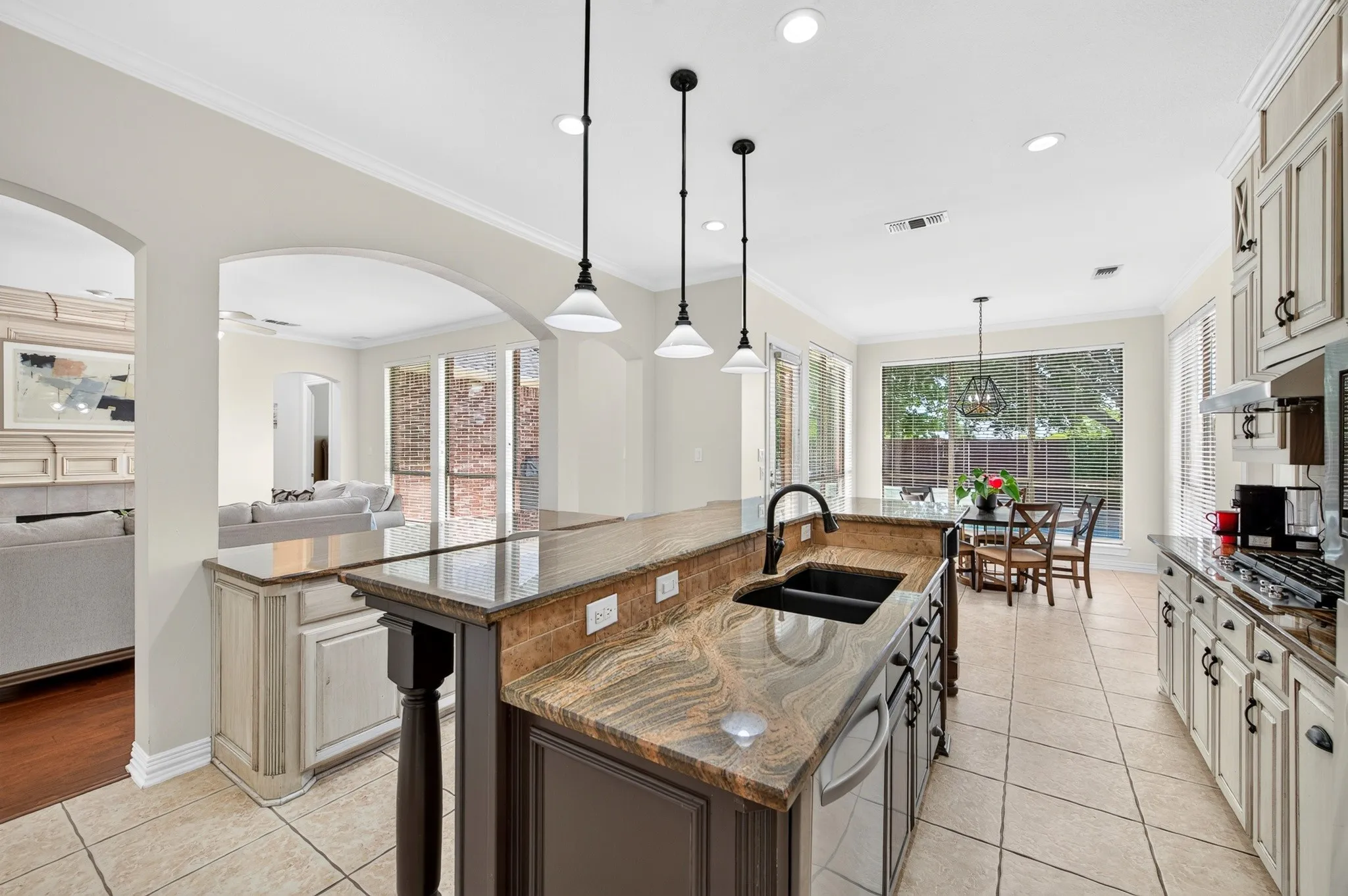 Gourmet kitchen featuring a large island with sink, stone countertops, stainless steel appliances, and abundant cabinetry