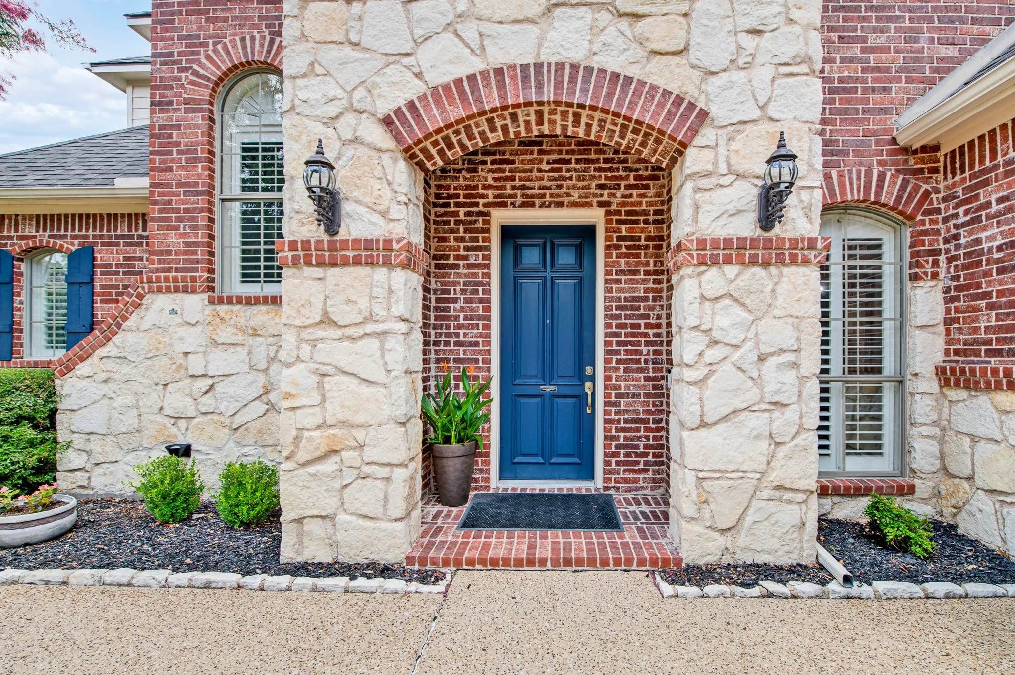 Stone and brick facade featuring a prominent arched entryway with a deep blue door