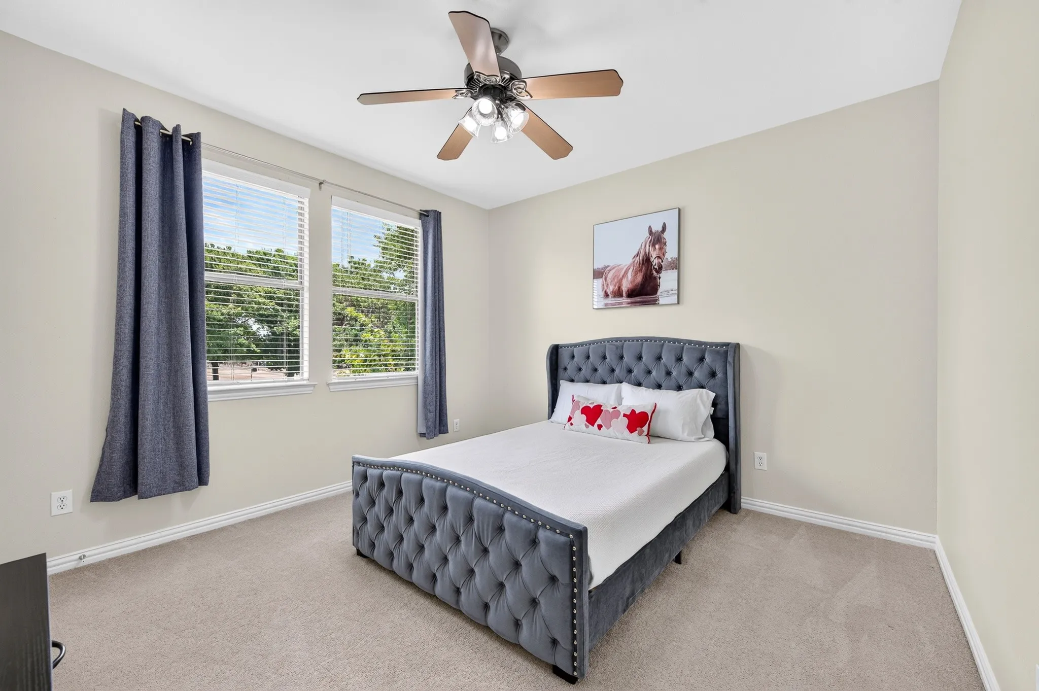 Carpeted room featuring two large windows with blinds and drapes, a ceiling fan with integrated lighting, and neutral wall paint