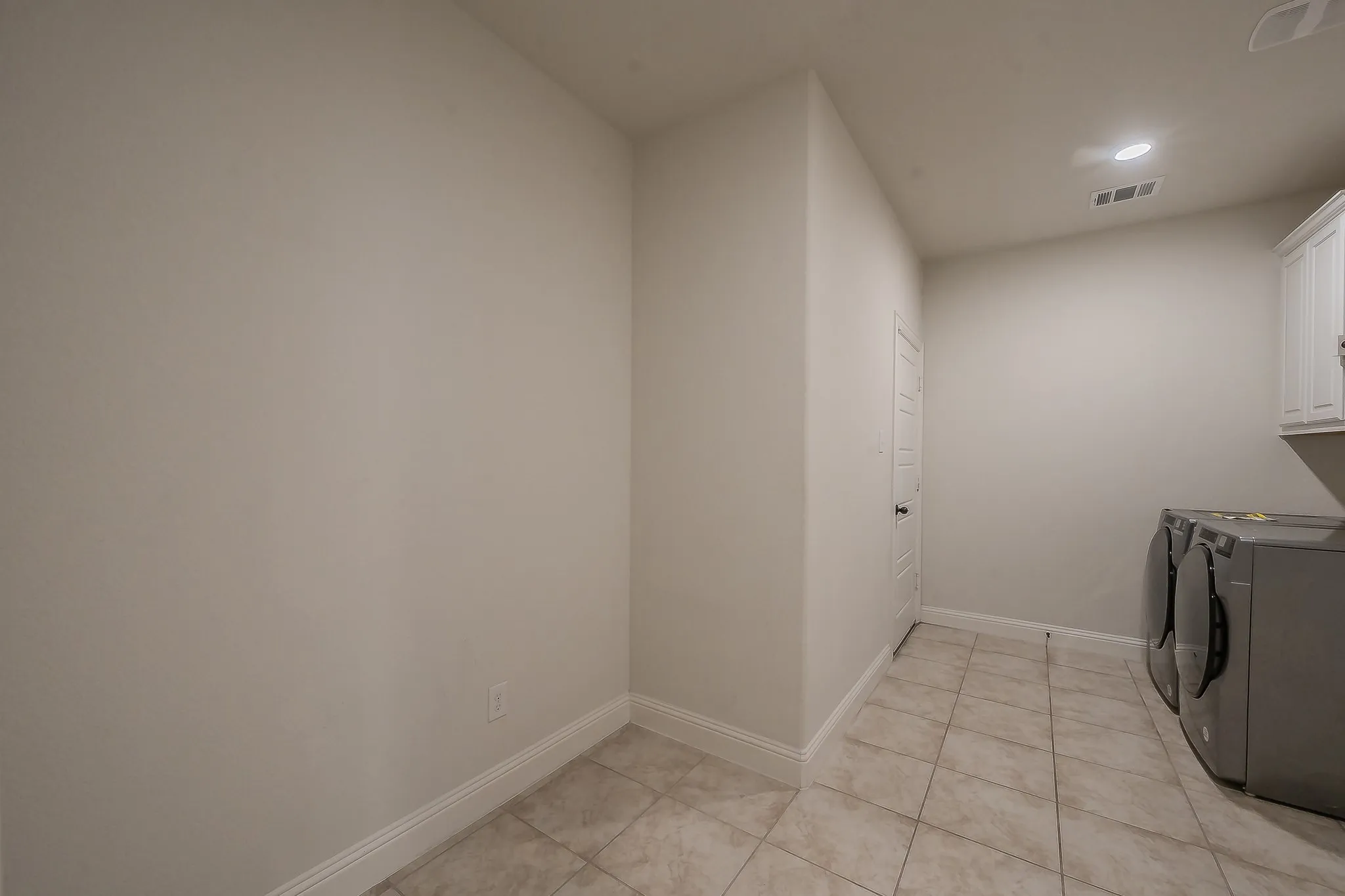 Utility room featuring tile flooring, recessed lighting, and white cabinetry