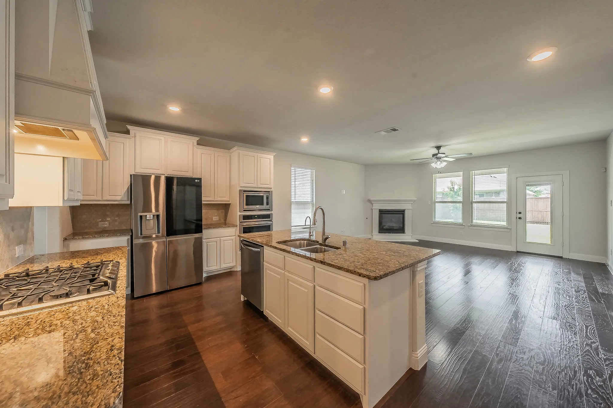 Open-concept kitchen with white cabinetry, stainless steel appliances, and a central island featuring a double-basin sink