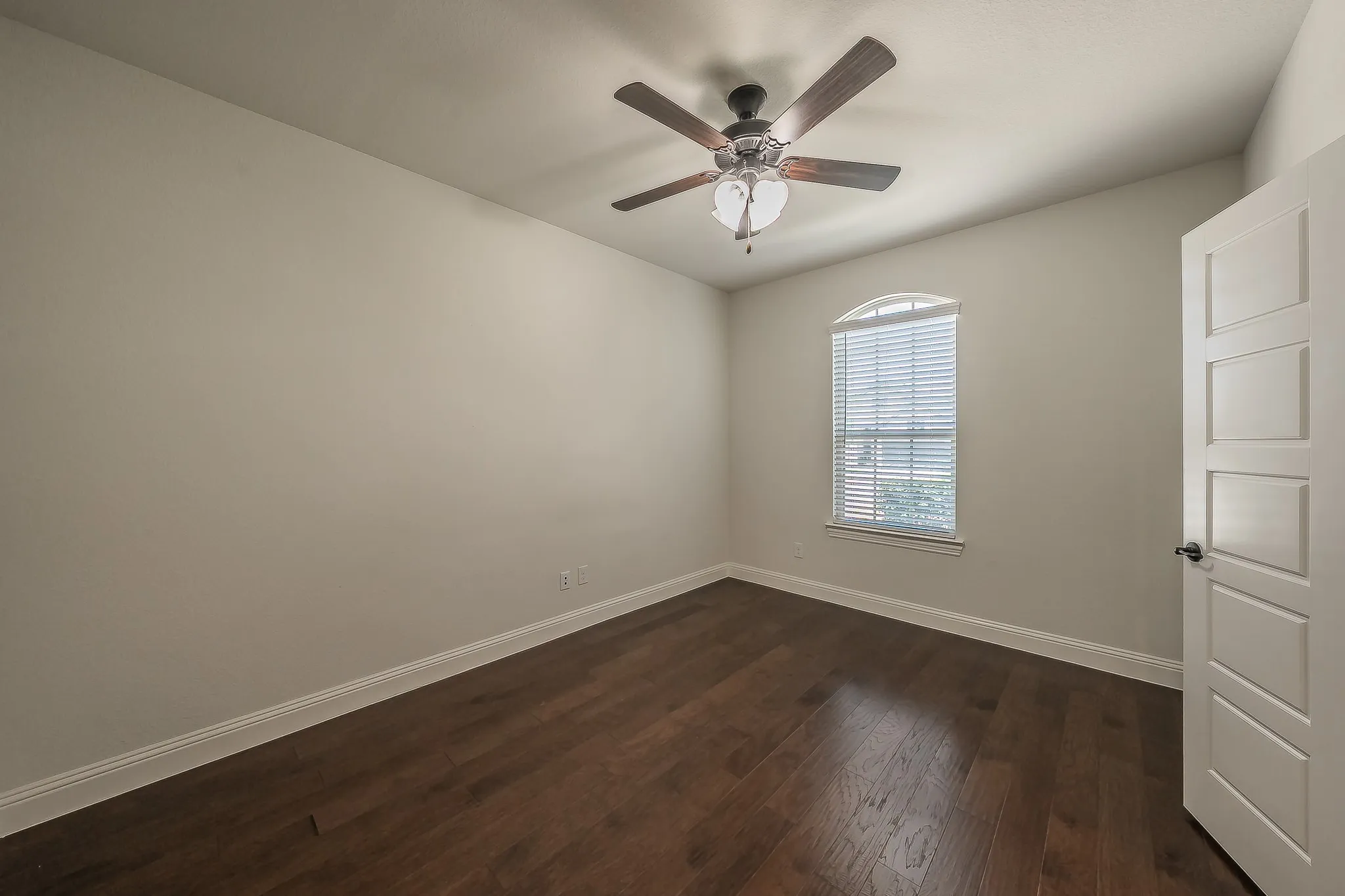 Neutral wall color, wood-finish flooring, white baseboards, and a contemporary ceiling fan with integrated lighting