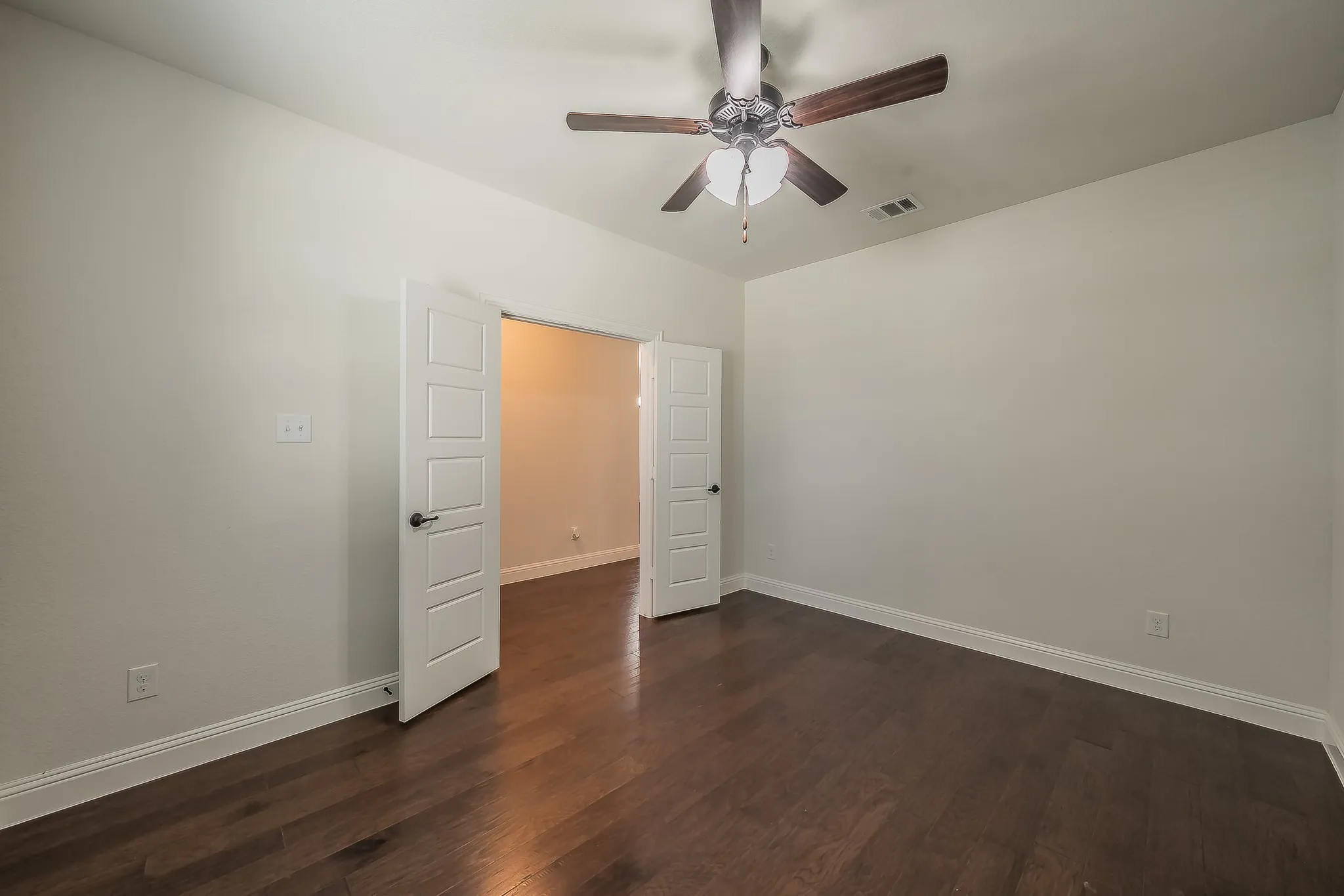 Room featuring dark wood-finish flooring, light neutral wall paint, and white baseboards