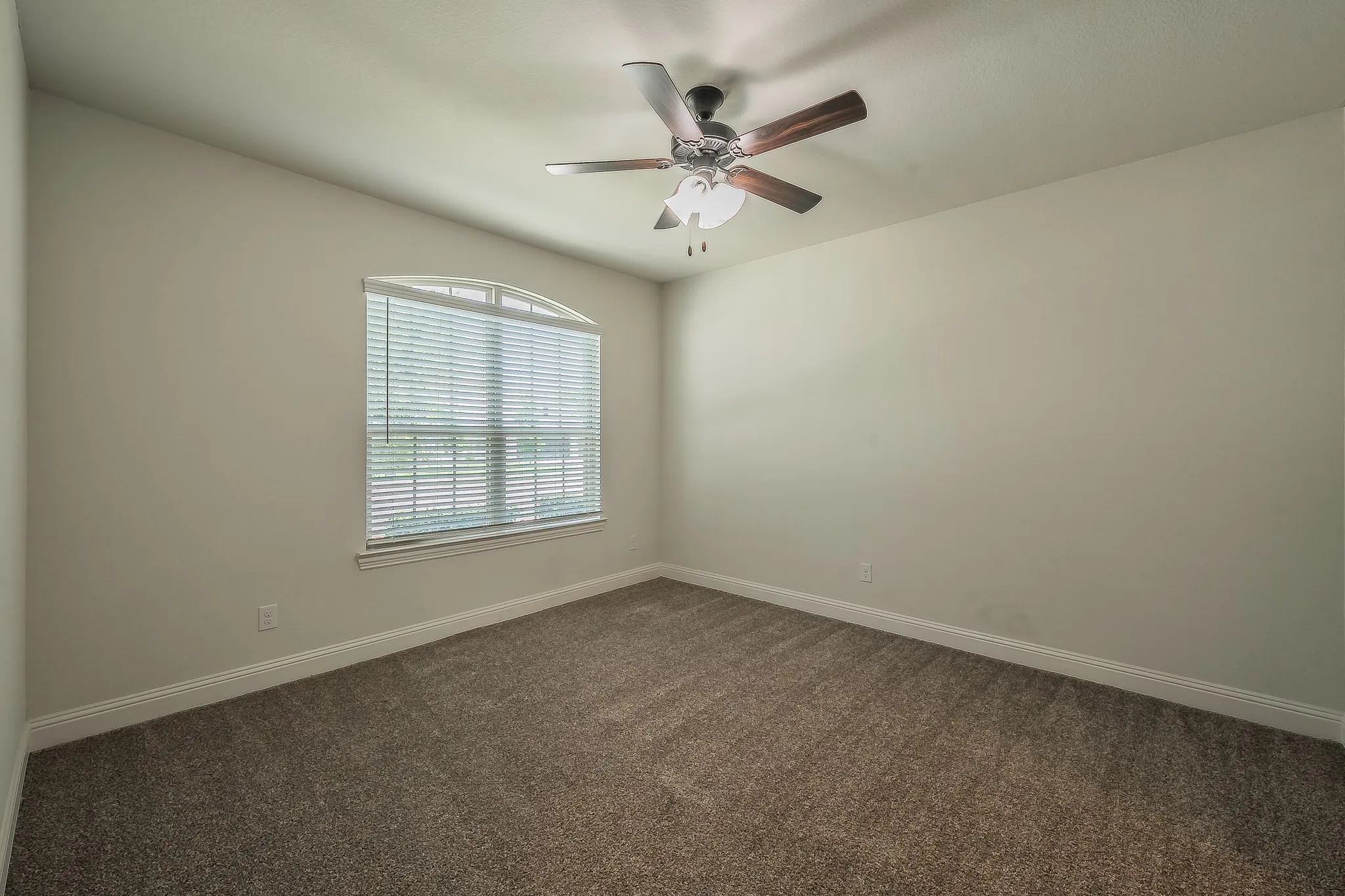 Neutral-toned room featuring a vaulted ceiling and textured carpet flooring