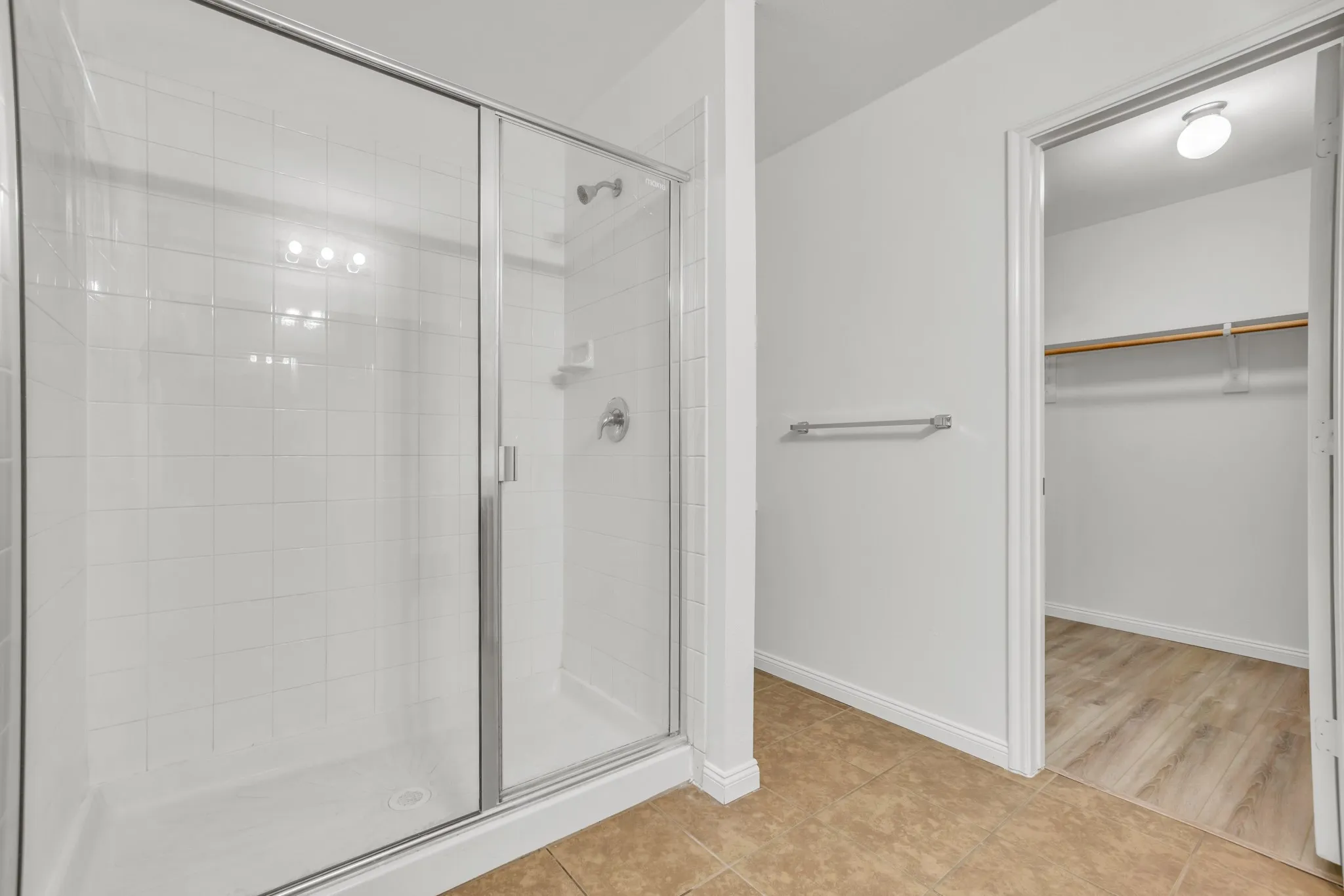 Tiled walk-in shower with clear glass enclosure and chrome fixtures