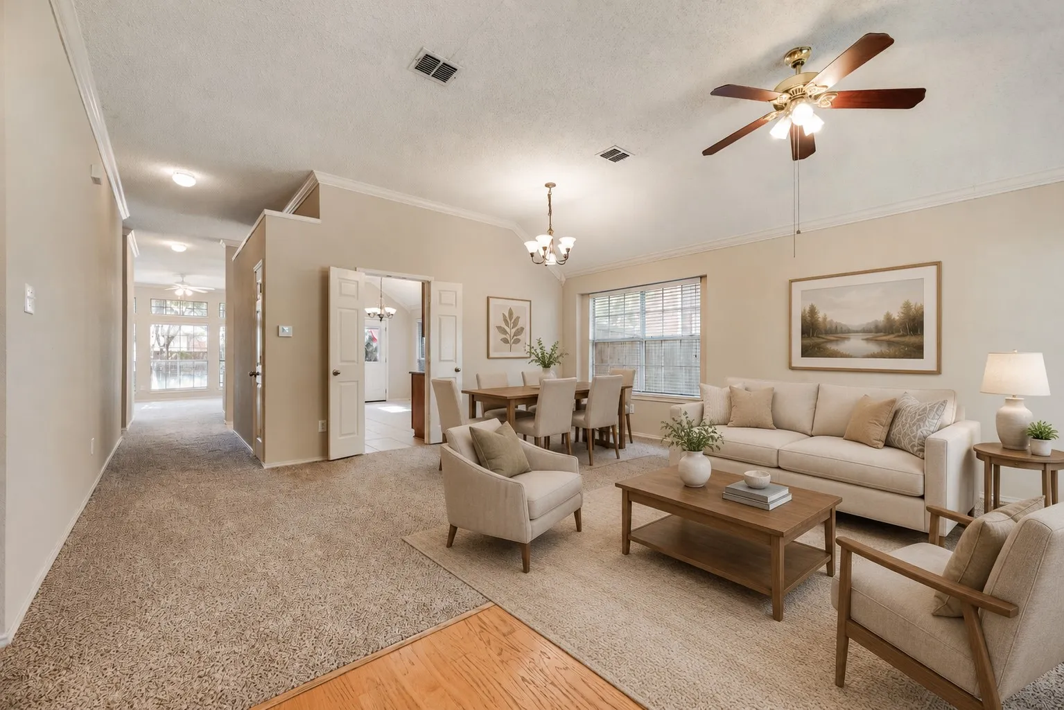 Living area featuring neutral-toned walls, vaulted ceilings, and a ceiling fan with light fixture